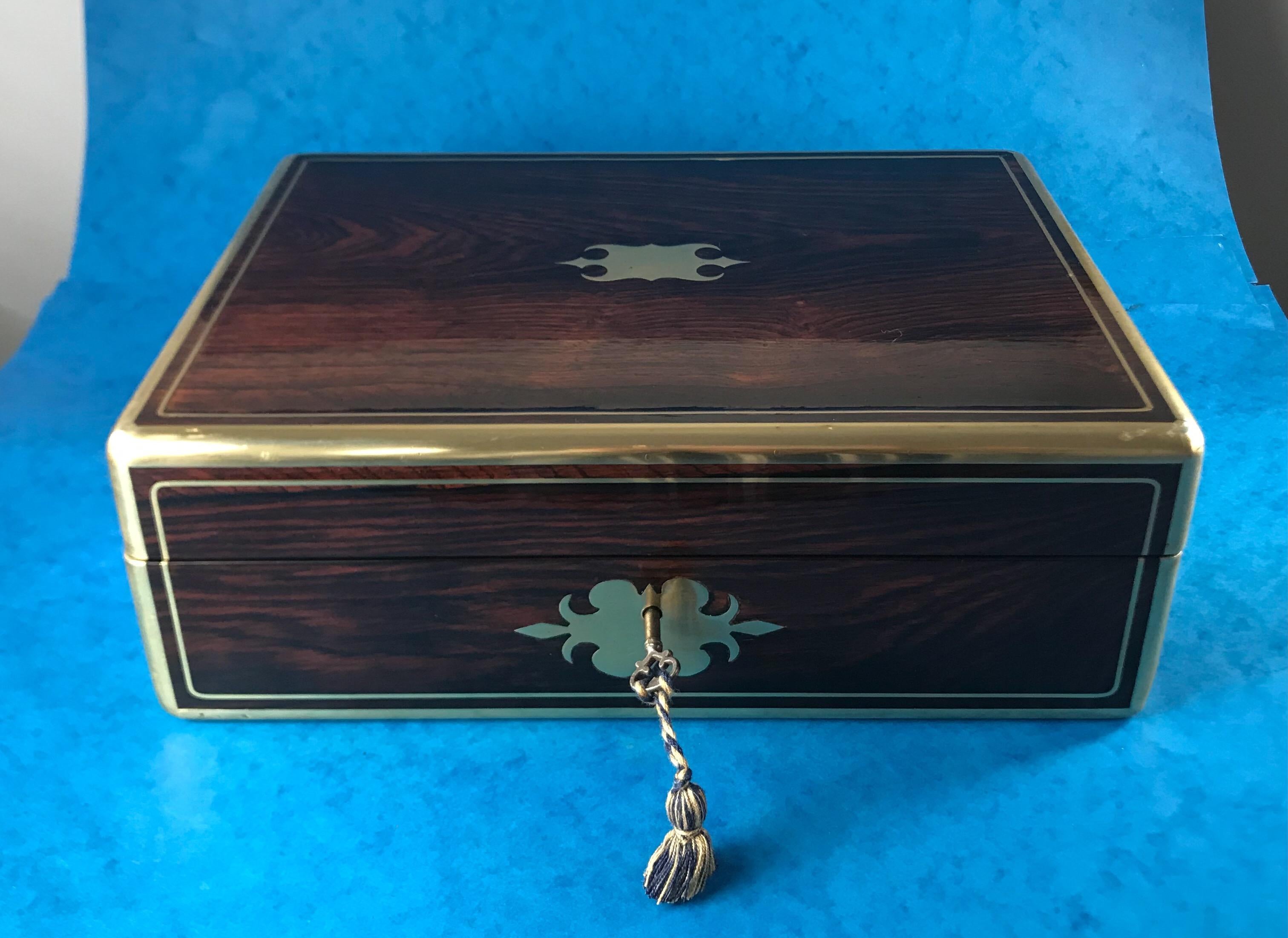A late Georgian William IV 1830 brass bound brass inlaid rosewood box, with flush handles to the side and a working lock and key. It’s a beautiful piece of rosewood.
It measures 34 by 25.5 and stands 12 cm high.
 