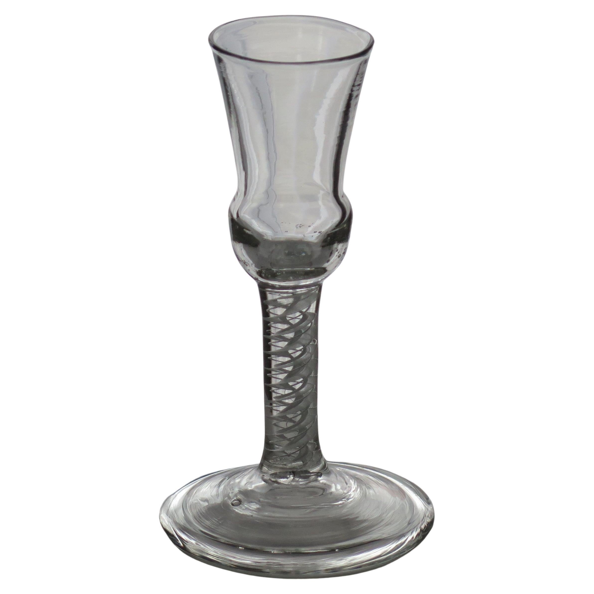 This is a superb hand-blown example of an English, mid-Georgian, wine or cordial drinking glass with a rare thistle bowl, thick double series opaque twist (DSOT) stem and wide folded foot, dating from the middle of the 18th century, circa