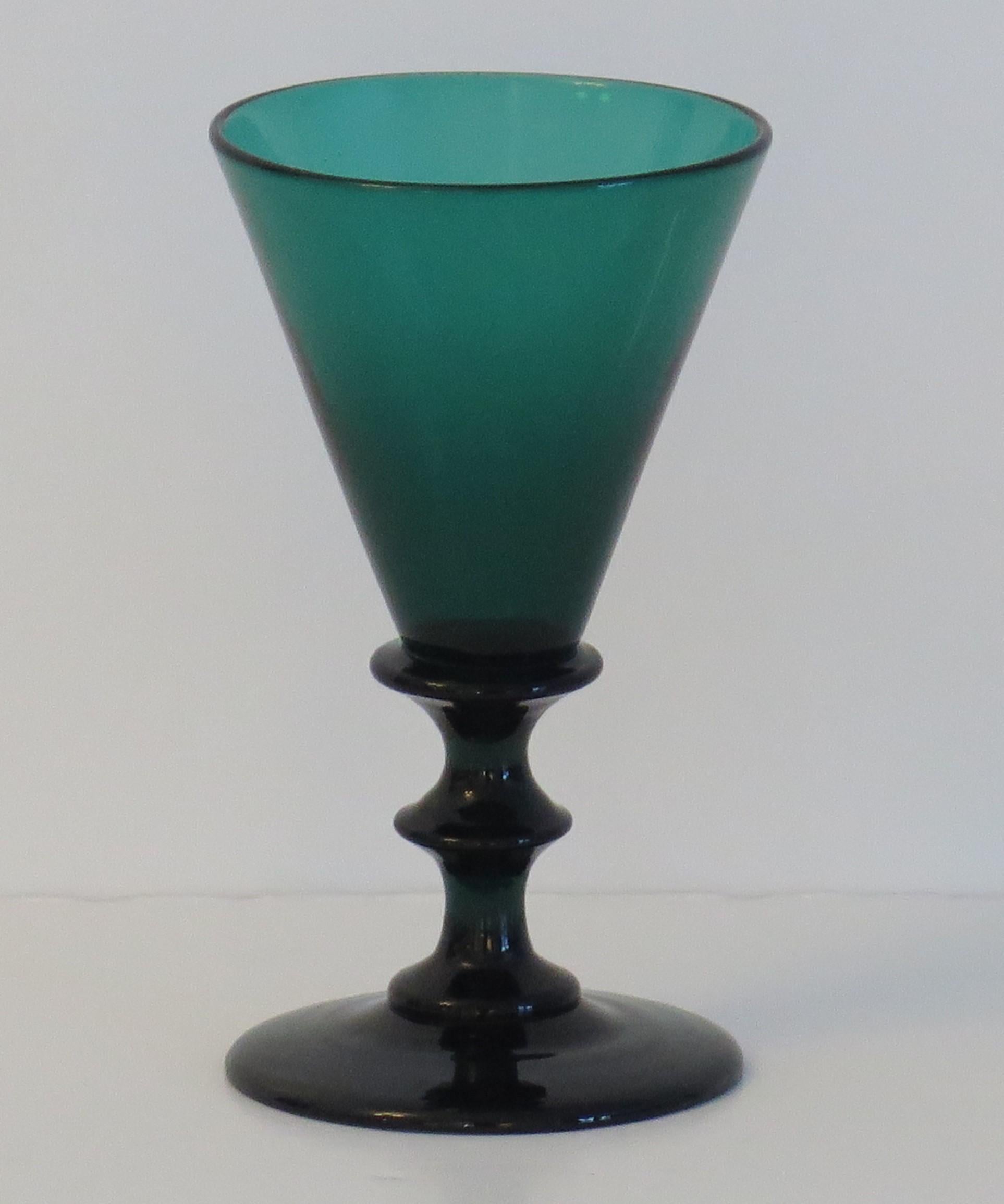 Se trata de un excelente ejemplo de copa de vino verde de Bristol, soplada a mano, inglesa, de principios del siglo XIX, que fechamos en el periodo de Regencia de Jorge 111, hacia 1815.

Este vaso tiene un elegante cuenco cónico con un gollete en el