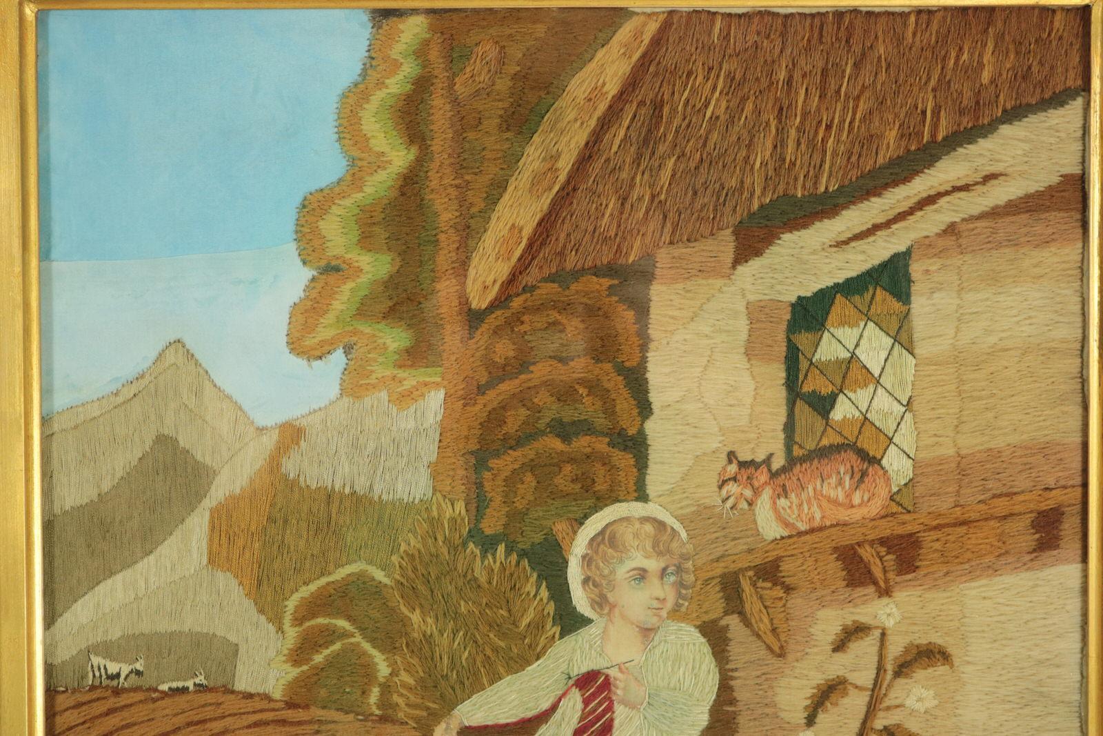 Victorian Woolwork picture of a child playing with a cat. Worked in wool and silk on linen and silk ground, in a variety of stitches. Pictorial scene set in a country landscape. Depicts a young boy sitting on a basket outside his house, holding a