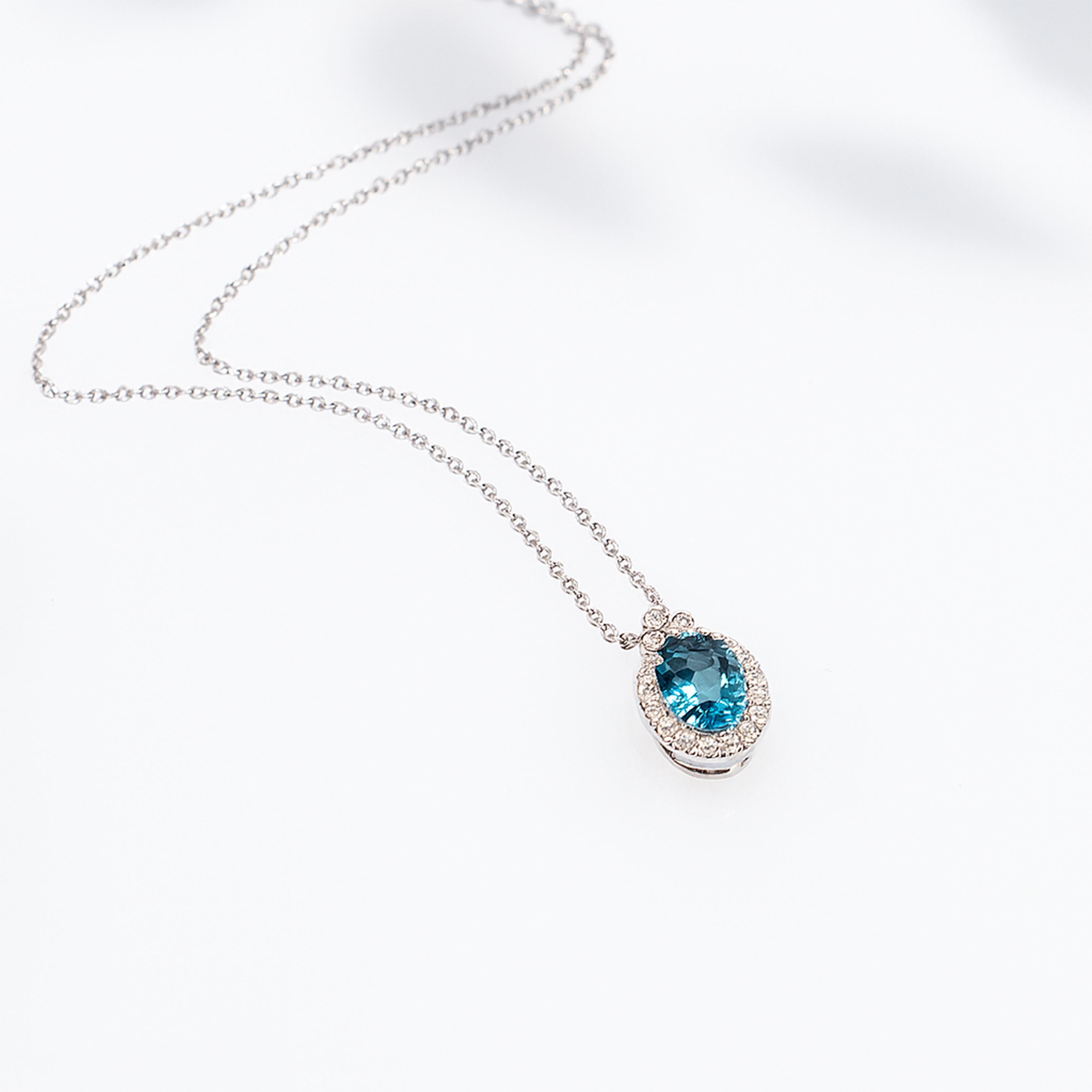 Georgios Collections présente un remarquable collier pendentif en or blanc 18 carats orné de topazes bleues et de diamants, fabriqué à la main à Athènes, en Grèce. Cette pièce élégante présente une topaze bleue de taille ovale, totalisant 0,86