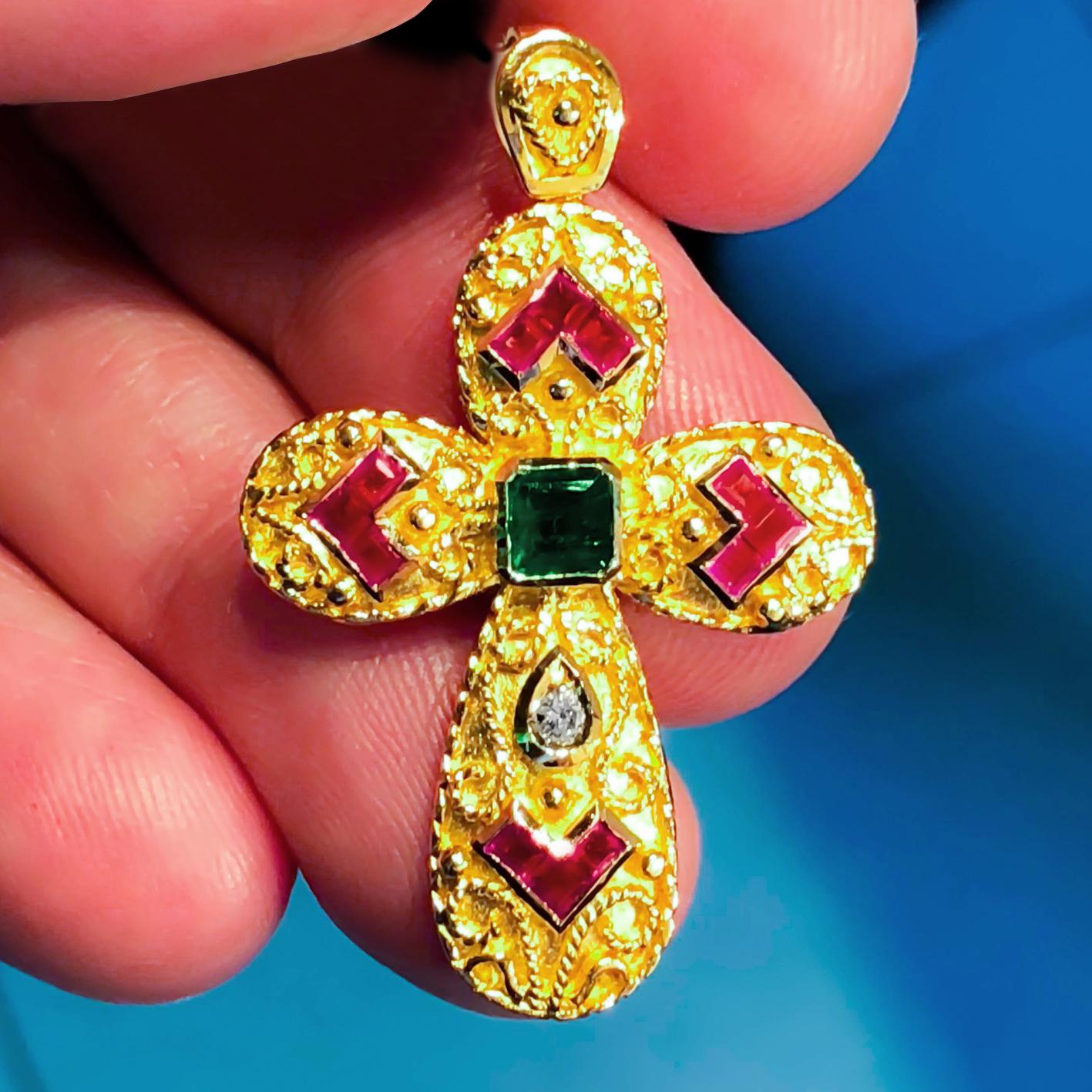 S.Georgios Byzantine Style Cross is handmade from solid 18 Karat Yellow Gold and has Granulation work and a mat beautiful finish. It features a center emerald cut Emerald total weight of 0,55 Carat, a Diamond total weight of 0,05 Carat, and Rubies