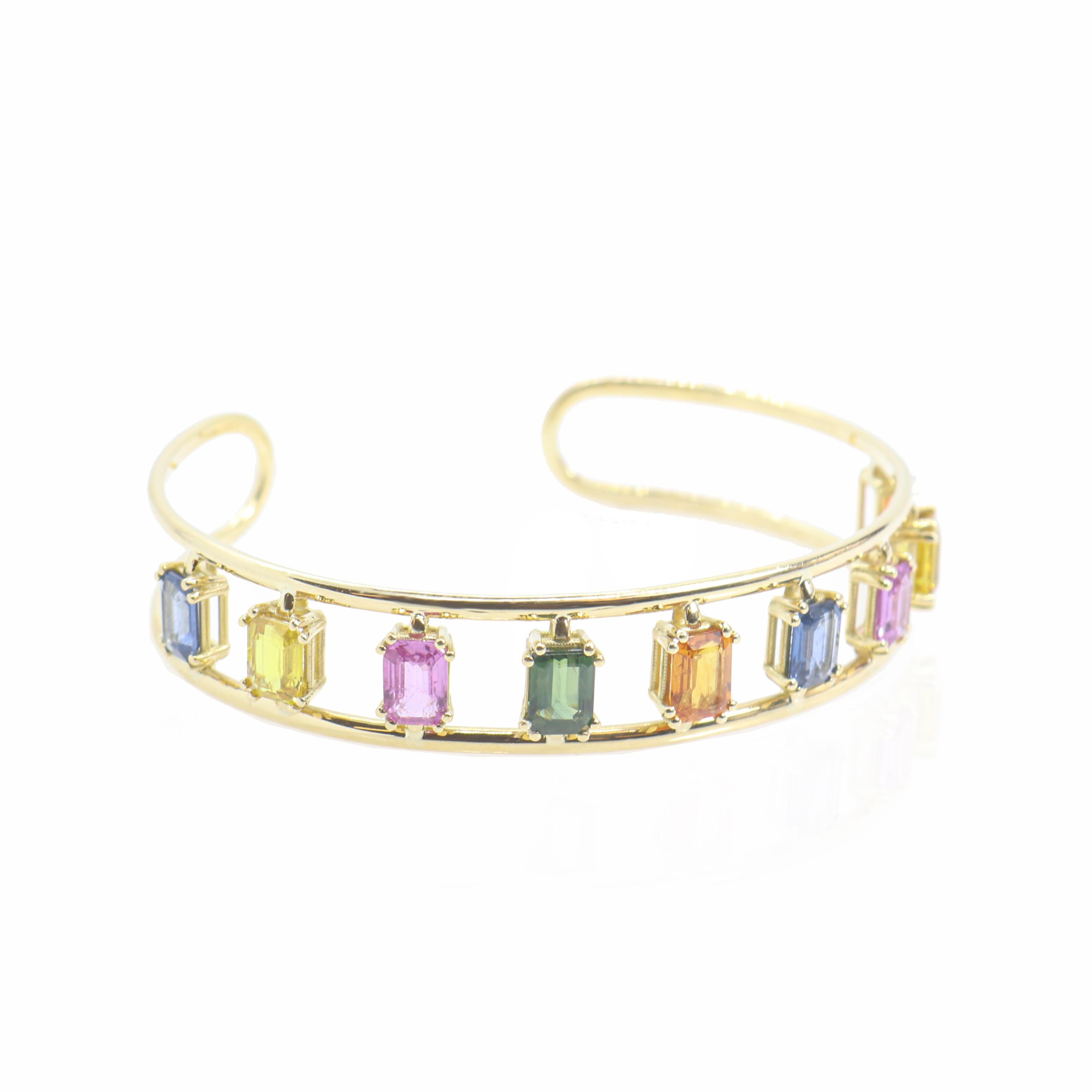 Véritable chef-d'œuvre d'élégance et de couleur, ce bracelet manchette en or jaune 18 carats de Georgios Collections est orné d'un ensemble de saphirs multicolores vibrants totalisant 10 carats. Chaque saphir est serti de manière experte pour créer
