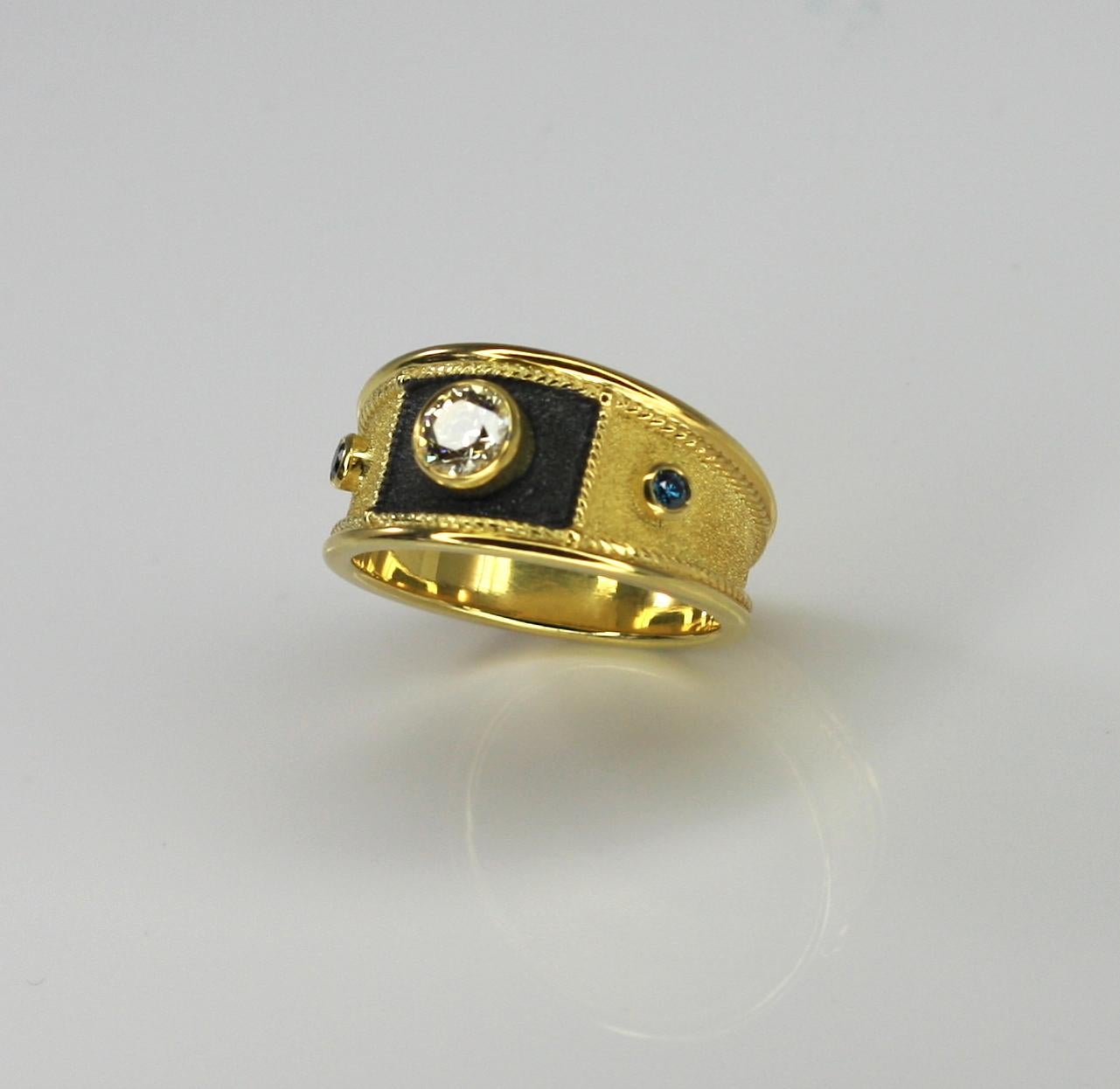 S.Georgios design ring handmade from solid 18 Carat Yellow Gold and decorated with granulation and Byzantine velvet background. The square front area surrounding the diamond is finished in Black Rhodium. This gorgeous unisex ring features 0.44 Carat