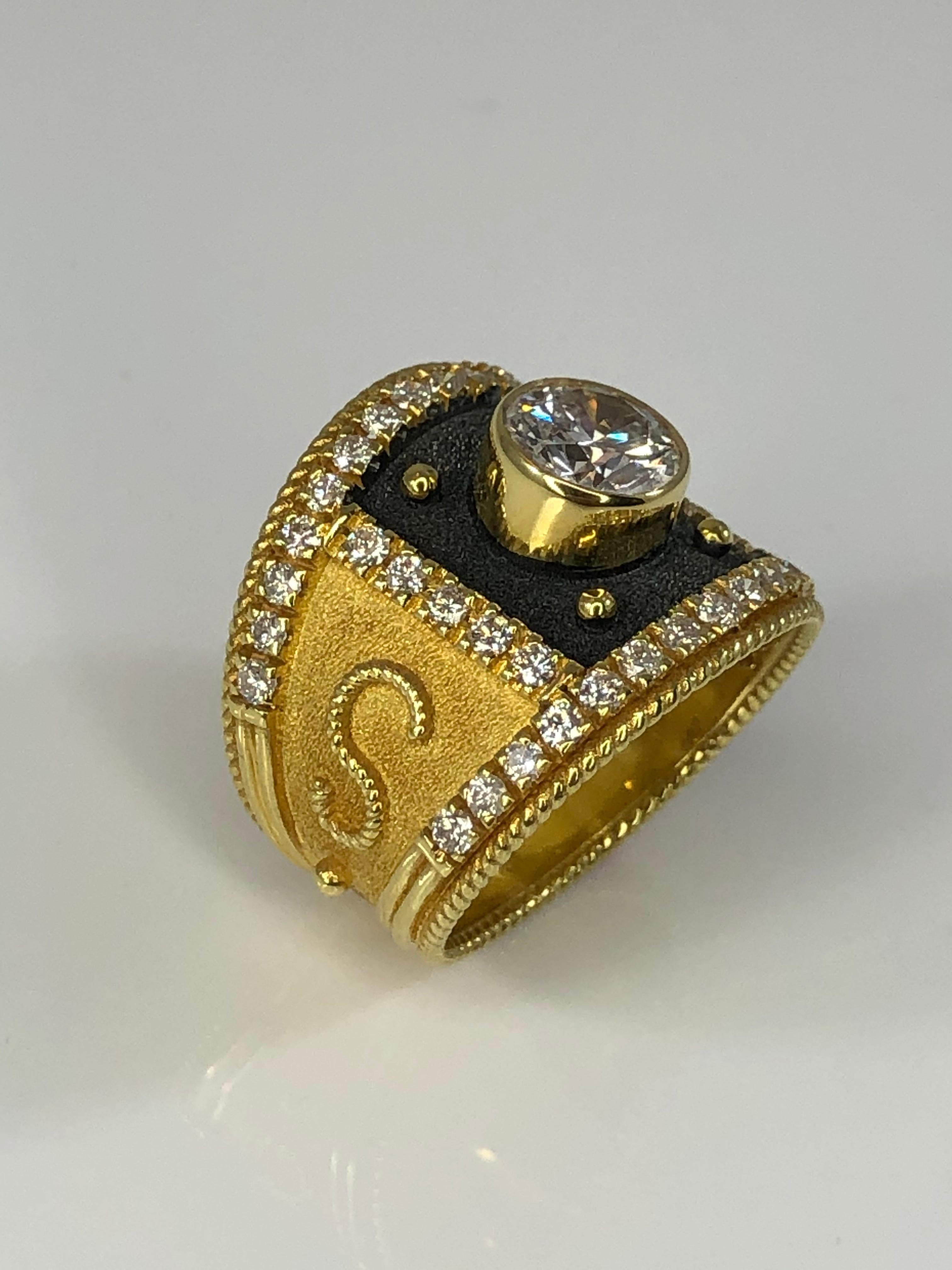 S.Georgios designer ring is handmade from solid 18 Karat Yellow Gold and is decorated with granulation details and a velvet background in Byzantine style. The front square area surrounding the diamond is finished with Black Rhodium. This ring