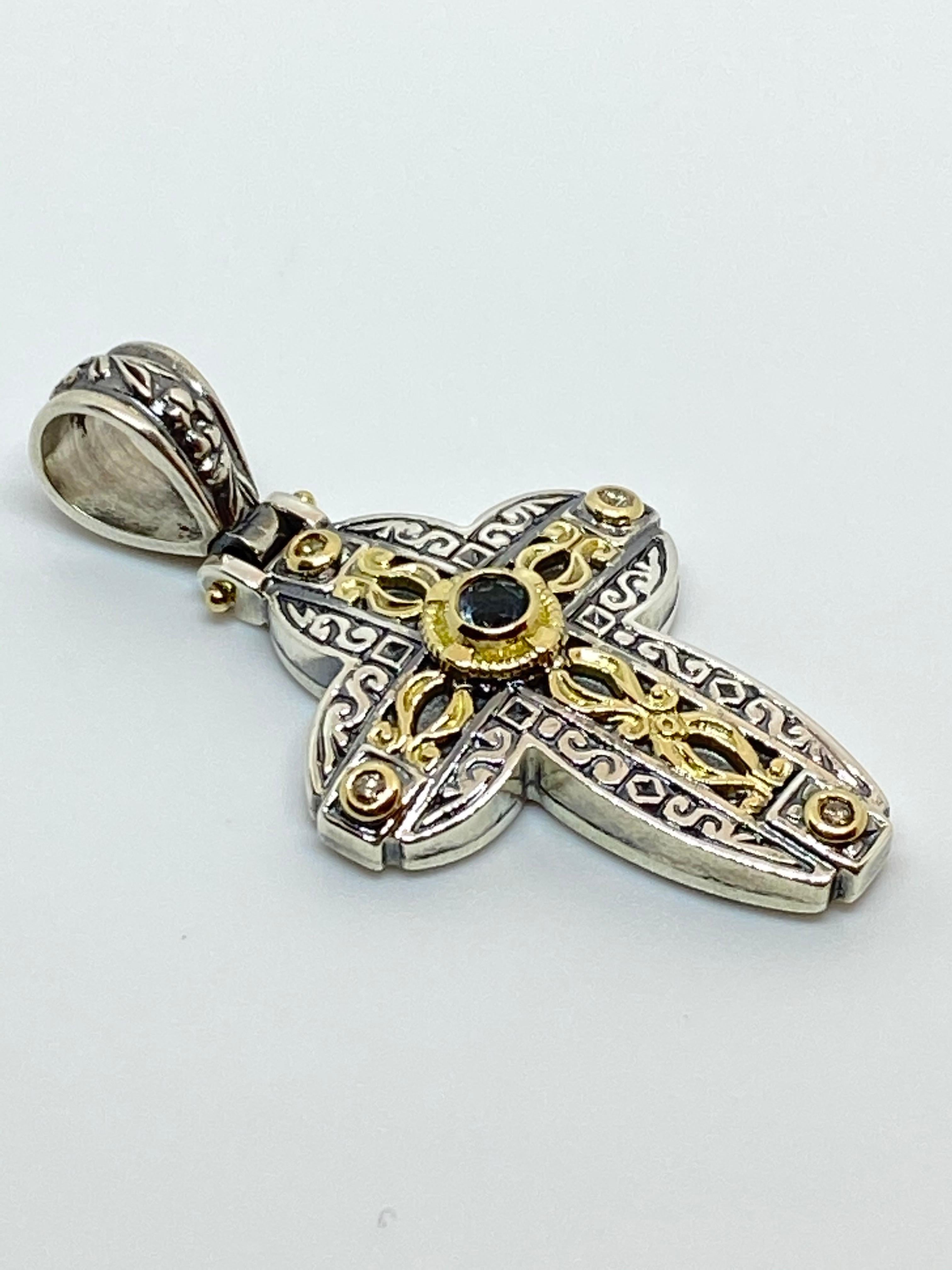 S.Georgios designer Silver and Gold 18 Karat two-tone Cross pendant is crafted from solid 18 Karat yellow gold pieces inlaid to create a unique look. This gorgeous cross enhancer features 4 Diamonds total weight of 0.12 Carat and a Blue Lopaz with a