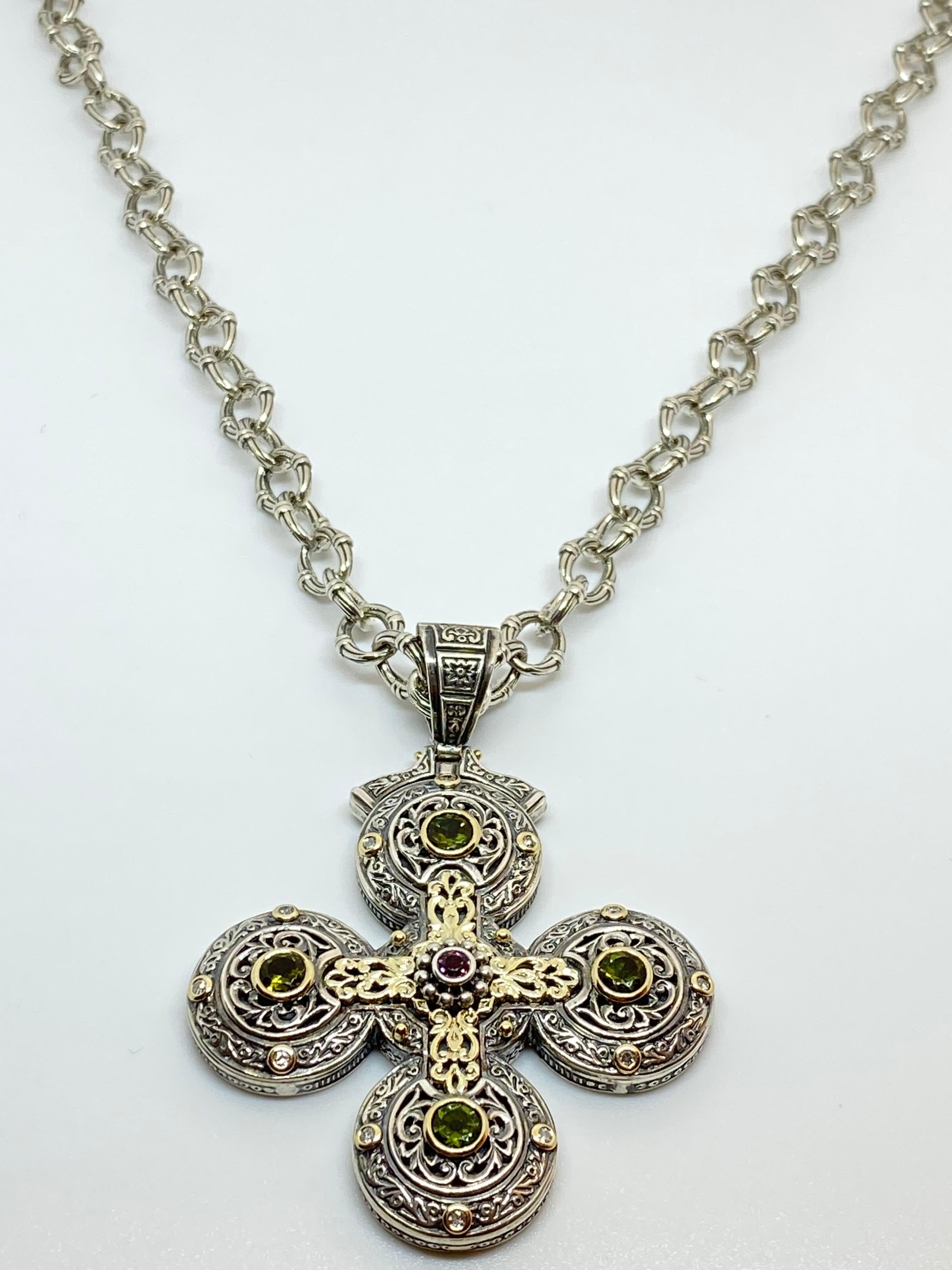 S.Georgios designer Silver and Gold 18 Karat two-tone Cross pendant is crafted from 18 Karat solid yellow gold pieces inlaid to create a unique look. This gorgeous cross enhancer features 12 Diamonds total weight of 0.24 Carat and 4 Tourmalines and