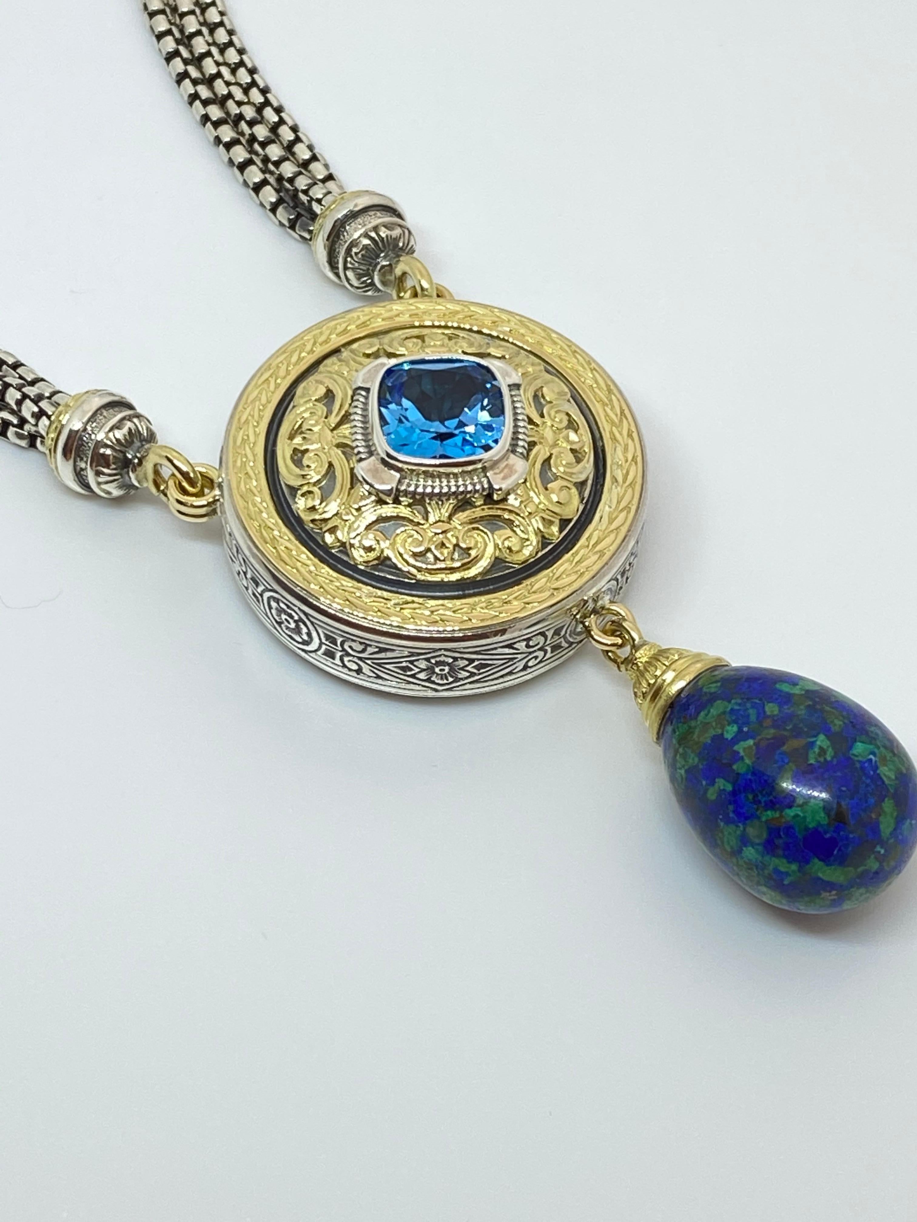 Voici le collier de pendentifs S.Georgios, fabriqué à la main en argent sterling et en or jaune 18 carats pour créer un look byzantin unique et élaboré. Ce superbe collier est composé d'une topaze bleu ciel de 4,55 carats, taillée en coussin, et