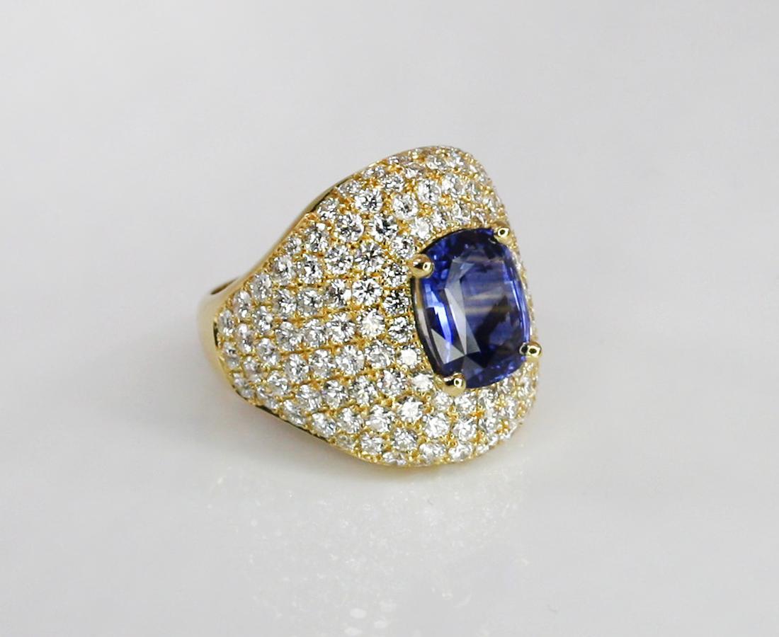 This S.Georgios gorgeous designer wide band Sapphire and Diamond Ring in 18 Karat Yellow Gold and all hand made. It features a stunning oval shape natural Sapphire total weight of 4.53 Carat encircled by natural white Diamonds brilliant cut VVS2
