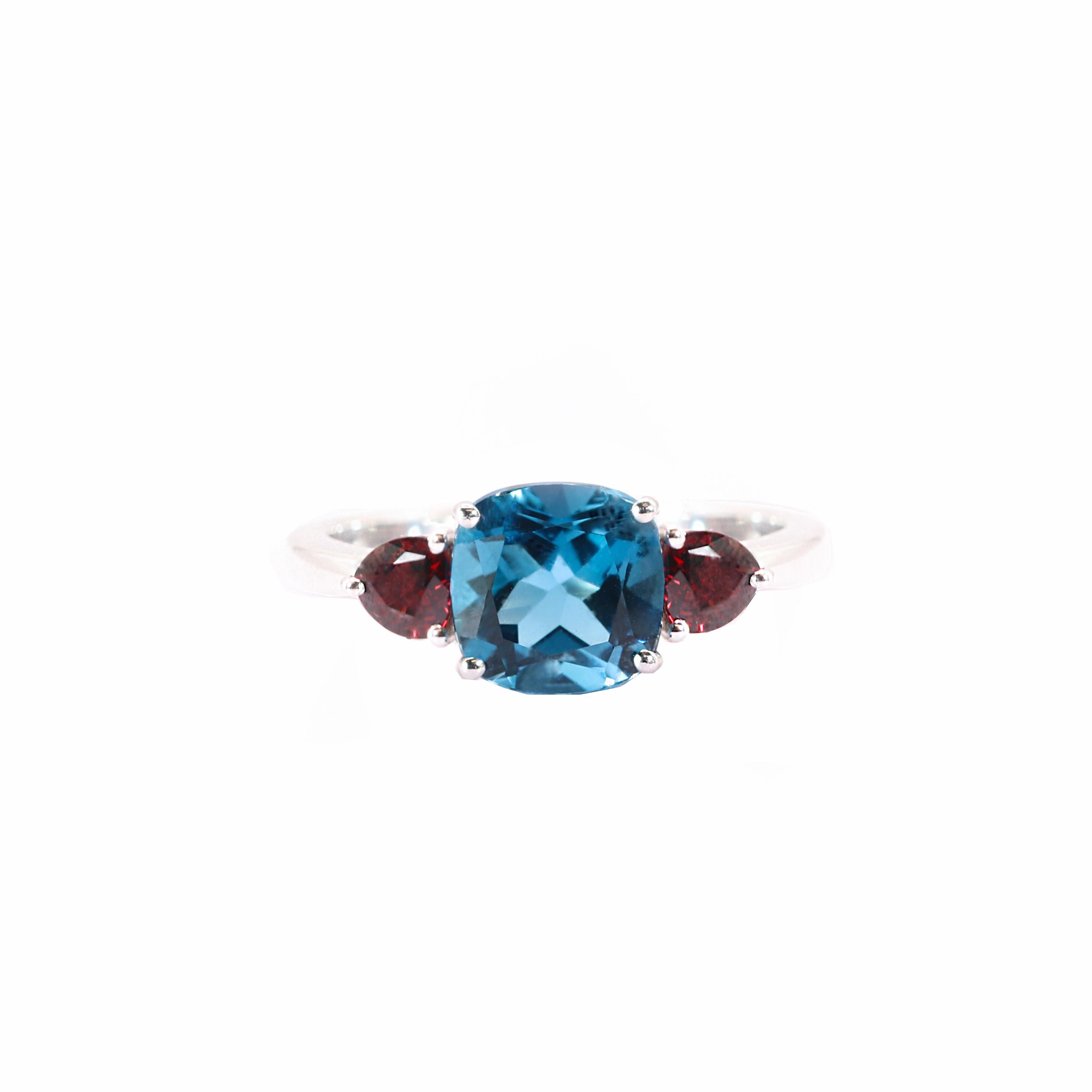 S.Georgios designer presents a cushion shape 2.73 Carats Blue Topaz Ring with two triangle Rubies with a total weight of 0.67 Carats. This simple yet stunning ring is handmade from 18 Karat White gold in Athens Greece. The ring features a beautiful