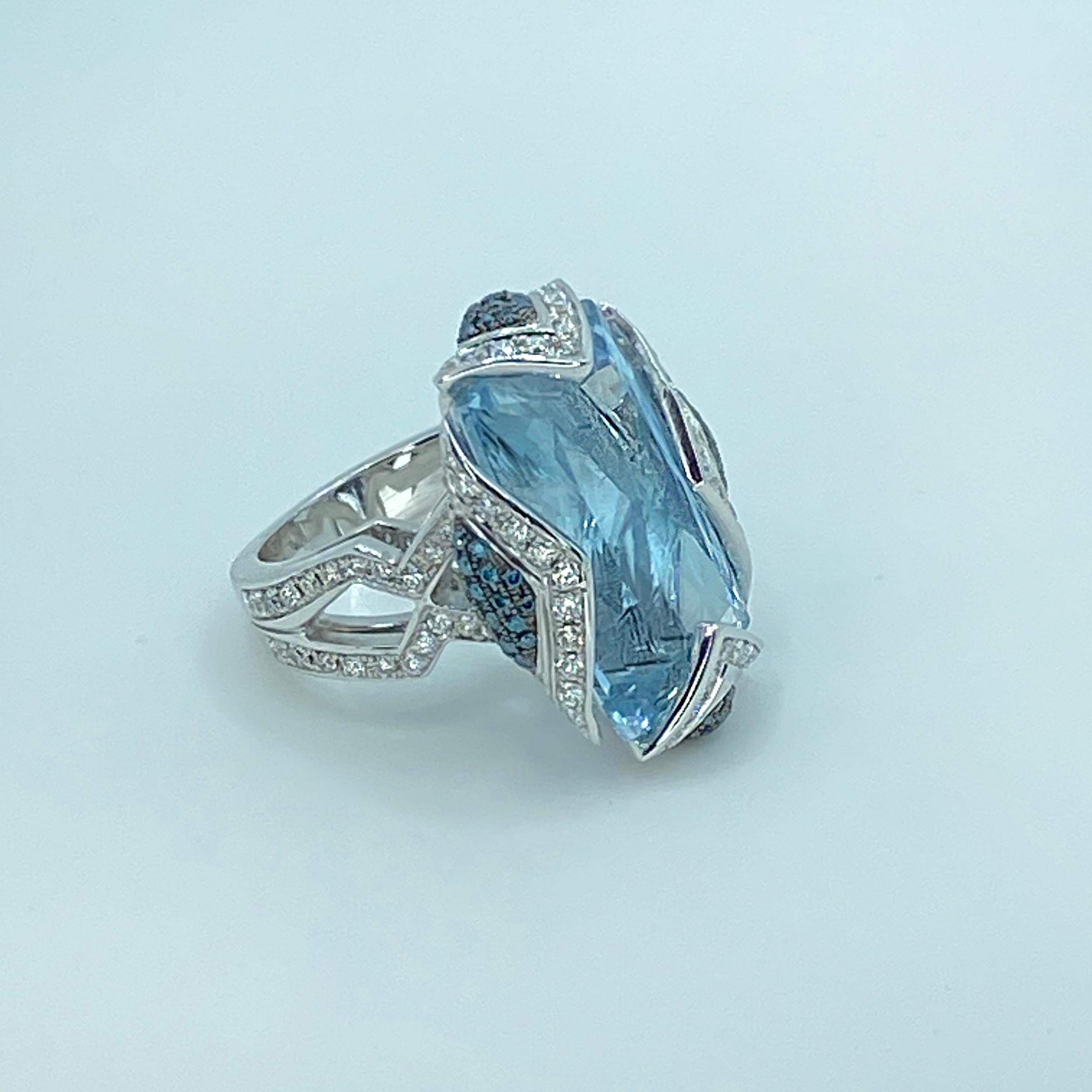 S.Georgios designer Ring is all hand-made in White Gold 18 Karat solitaire Aquamarine, Blue and White Diamonds. This stunning ring features a solitaire Cushion cut natural Aquamarine total weight of 28.25 Carat, surrounded by brilliant-cut white 