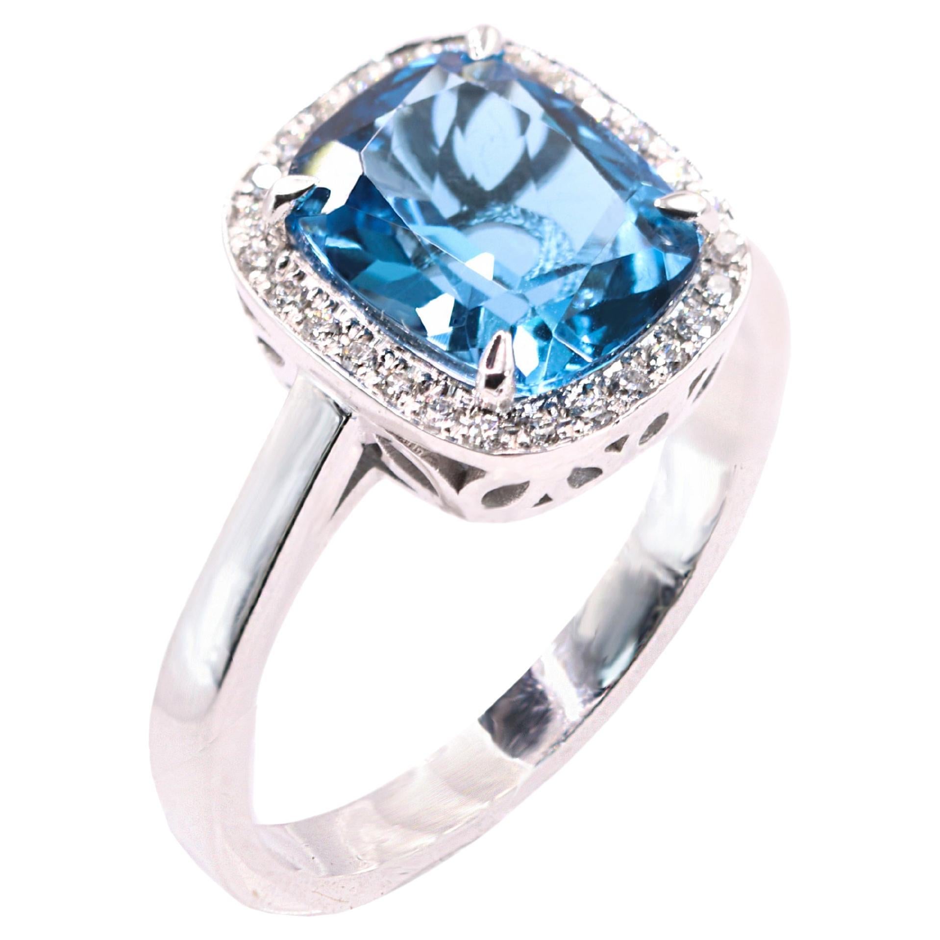 S.Georgios designer presents an oval shape 3.53 Carats Blue Topaz ring with a White Diamond Bezel with a total weight of 0.15 Carat weight. This simple yet stunning ring is handmade from 18 Karat White Gold in Athens Greece. The ring features a