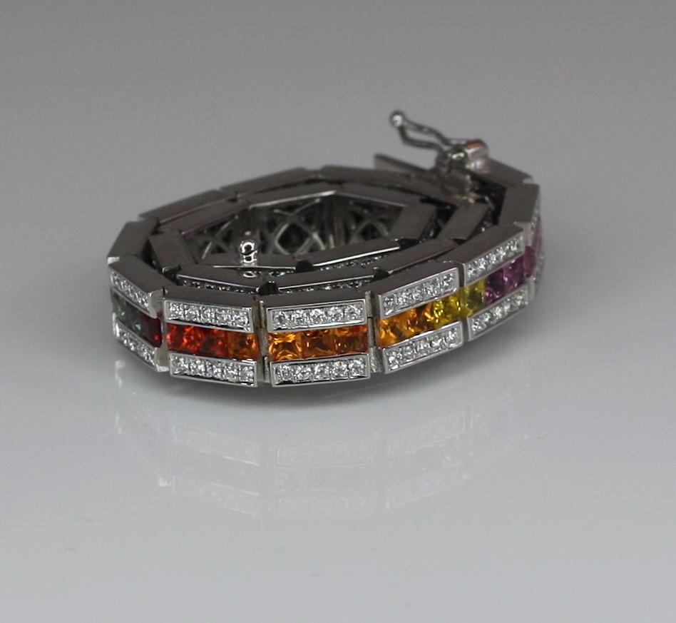 S.Georgios designer is presenting an 18 Karat Solid White Gold Bracelet with a row of invisible set Rainbow color Princess Cut Sapphires total weight of 9.25 Carat and brilliant-cut white Diamonds on the sides total weight of 1.75 Carat. The