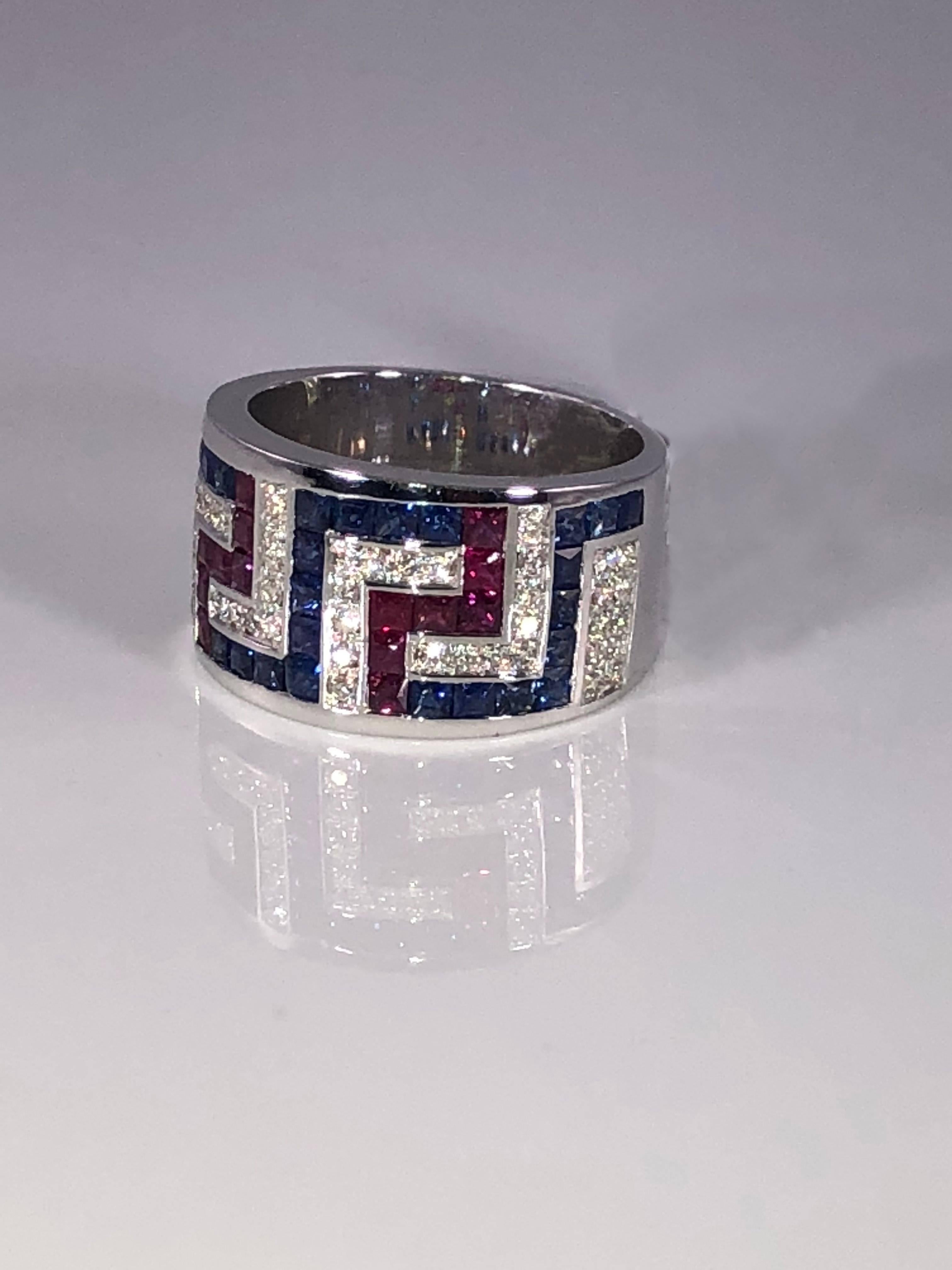 S.Georgios designer 18 Karat White Gold Ring featuring the Greek Key design symbolizing eternity. It is decorated with Brilliant Cut White Diamonds total weight of 0.35 Carat, Princess cut Rubys total weight of 0.64 Carat and Princess cut Blue