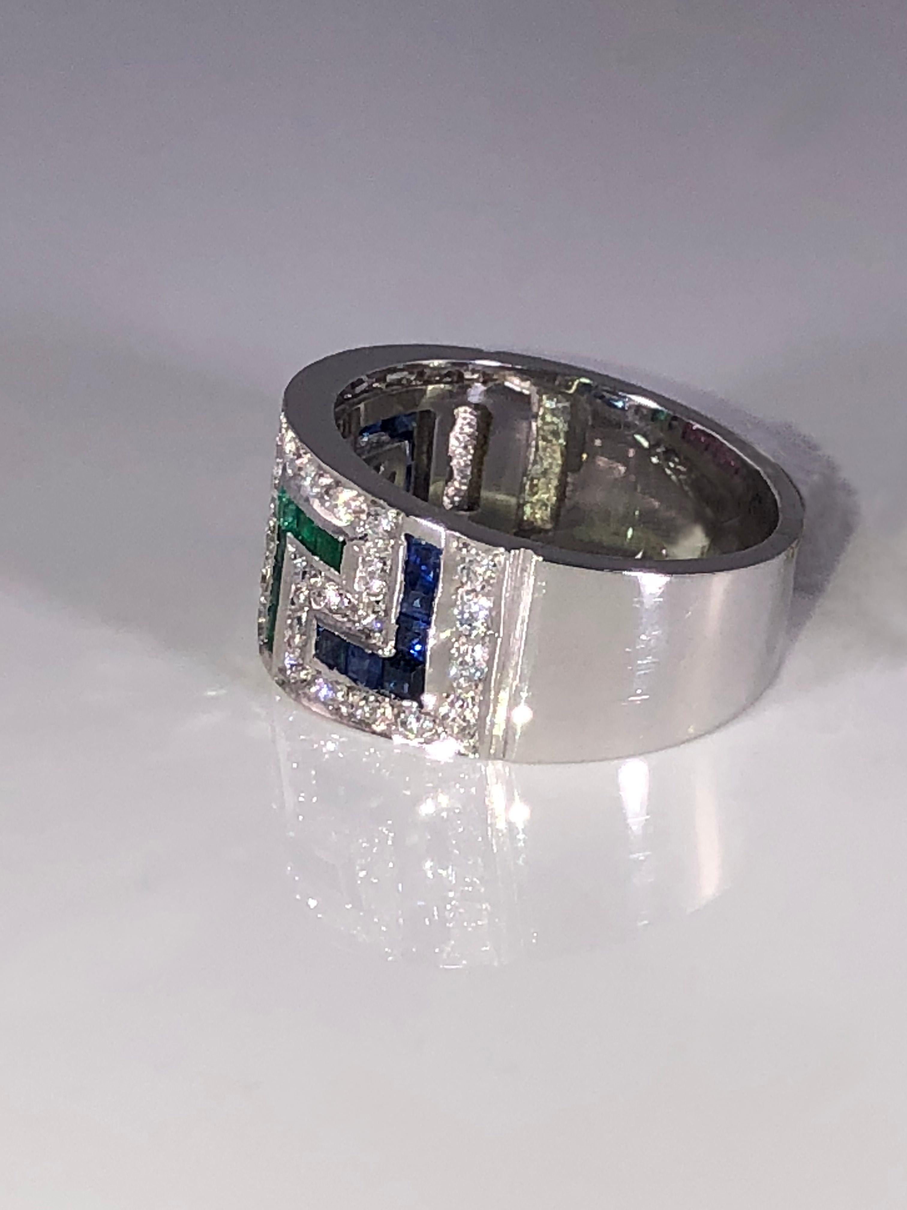 Bague en or blanc 18 carats du designer S.Georgios, ornée du motif de la clé grecque symbolisant l'éternité. Il est orné de diamants blancs taille brillant d'un poids total de 0,44 carat et de rubis, saphirs et émeraudes taille princesse d'un poids