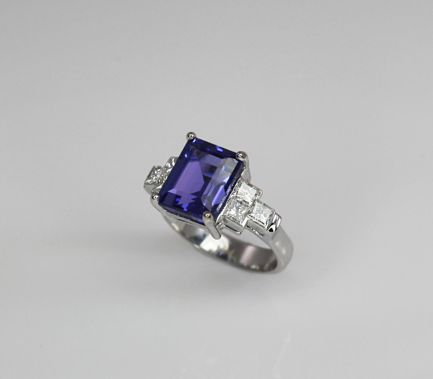 This S.Georgios designer Ring is all hand-made in 18 Karat White Gold and features a stunning Spotless Emerald cut natural Tanzanite total weight 6.01 Carat, surrounded by 6 princess cut VVS1 clarity and color F white Diamonds total weight of 0.88