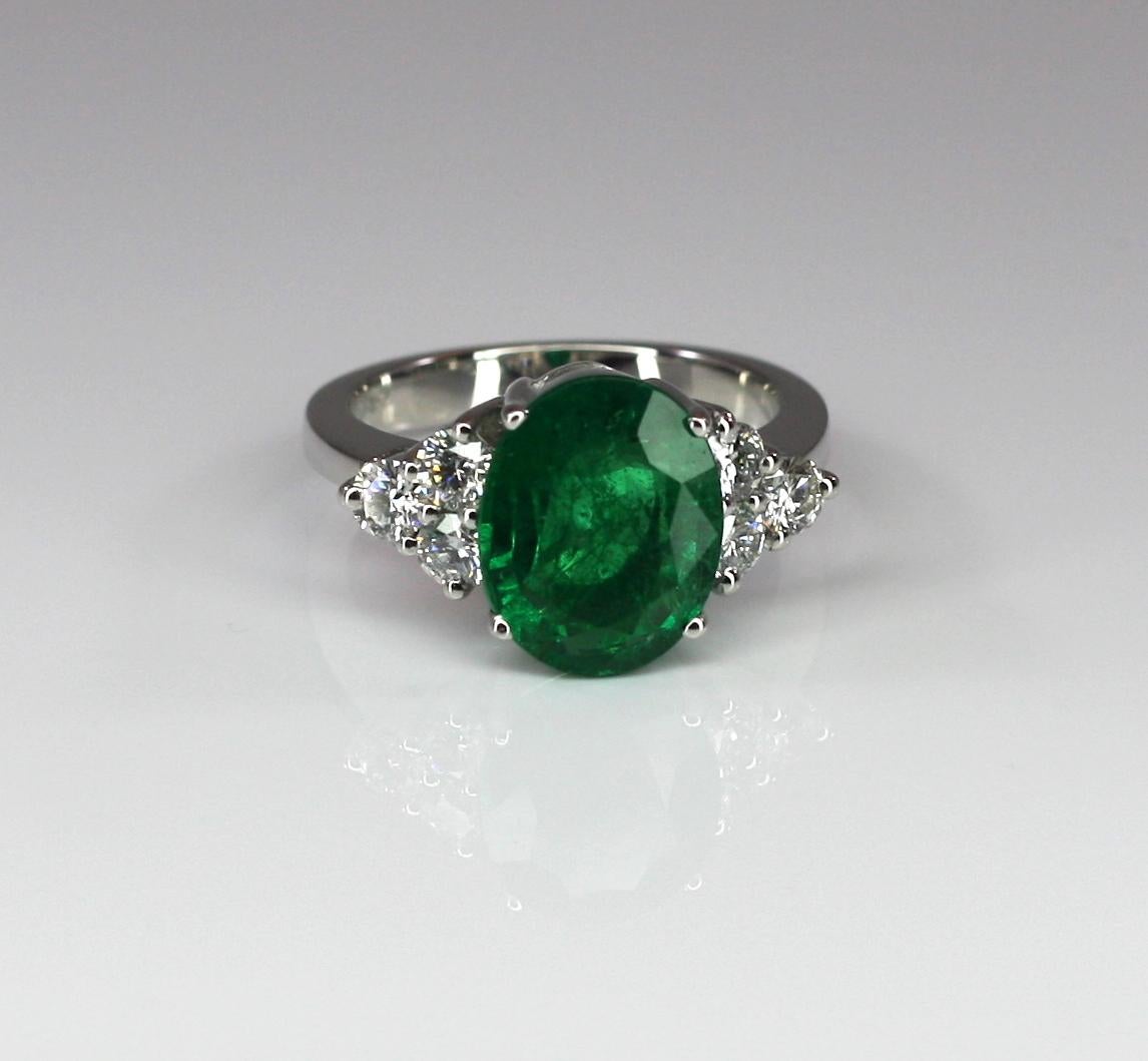 S.Georgios designer Solitaire Emerald and Diamond Ring is all hand-made in 18 Karat White Gold and features a stunning color solitaire oval cut natural Emerald total weight 3.90 Carat surrounded by 6 natural brilliant cut VS1 clarity and color F