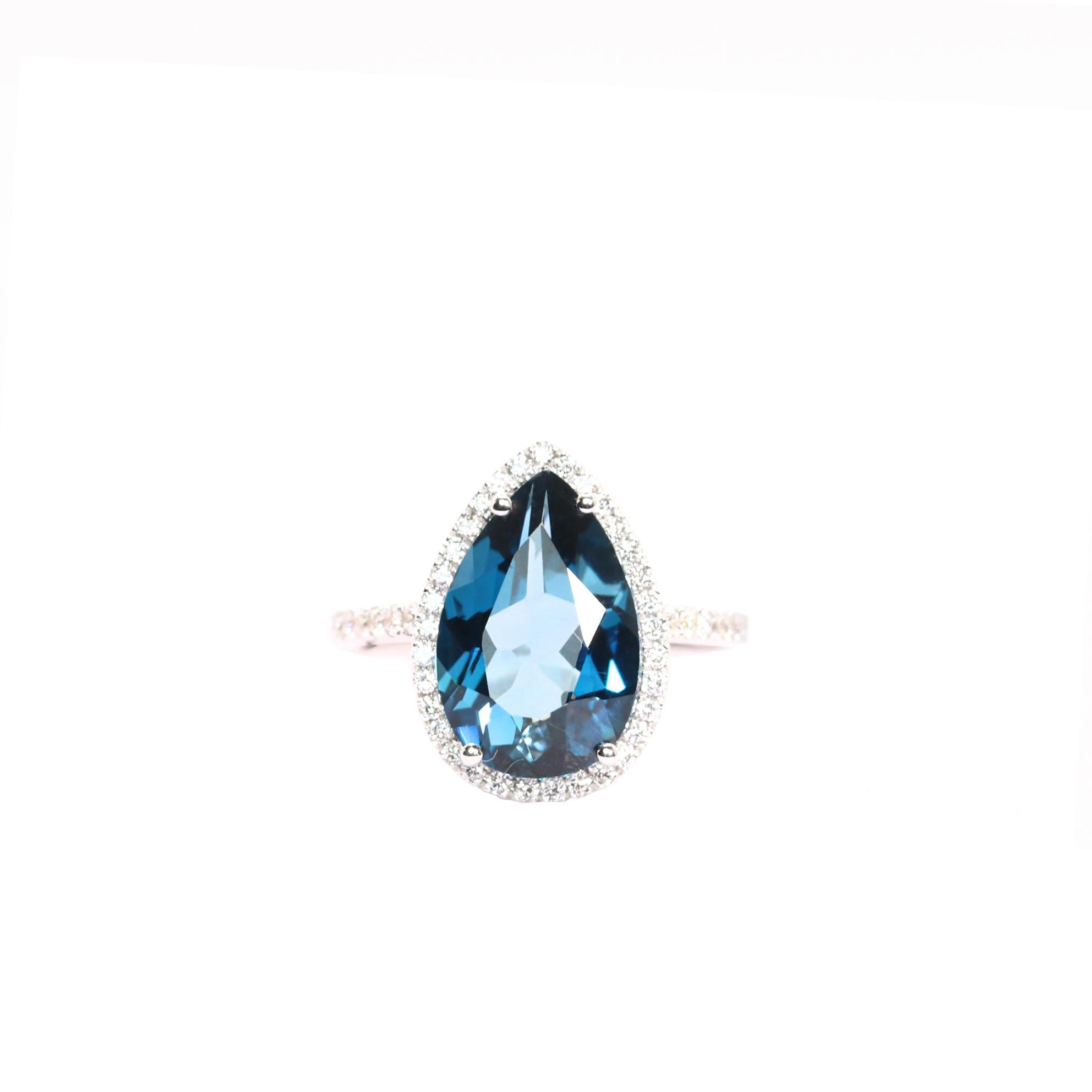 S.Georgios designer presents an exquisite 18 Karat White Gold ring featuring a pear-cut 6.60 Carats Blue Topaz at its center, framed by a dazzling bezel of White Diamonds, total weight of 0.45 Carats. The Blue Topaz boasts a rich, vibrant blue hue