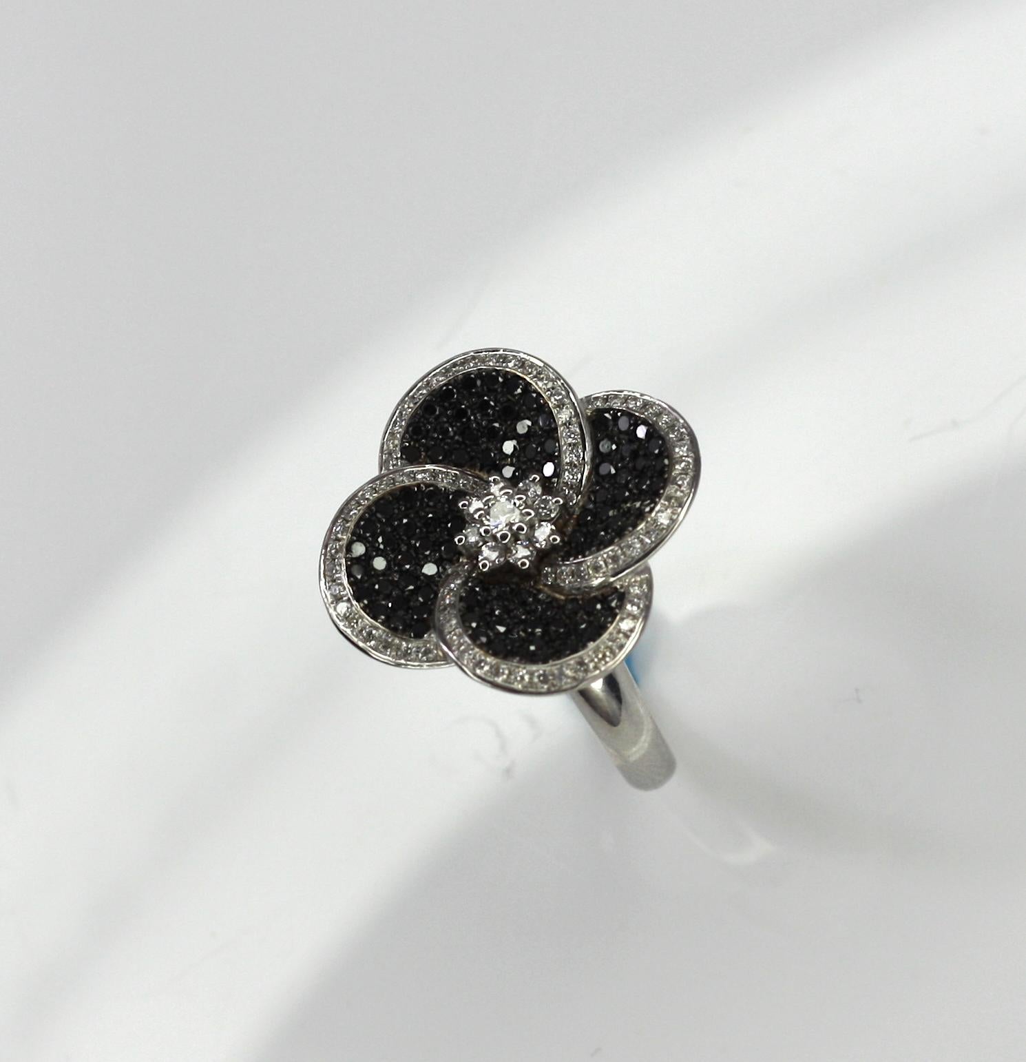 S.Georgios Floral 18 Karat White gold ring is all handmade and is decorated with Brilliant cut Diamonds shaped like flower petals. The Black diamonds are a total weight of 0,70 Carats and the white diamonds a total weight of 0.45 Carat. 
This