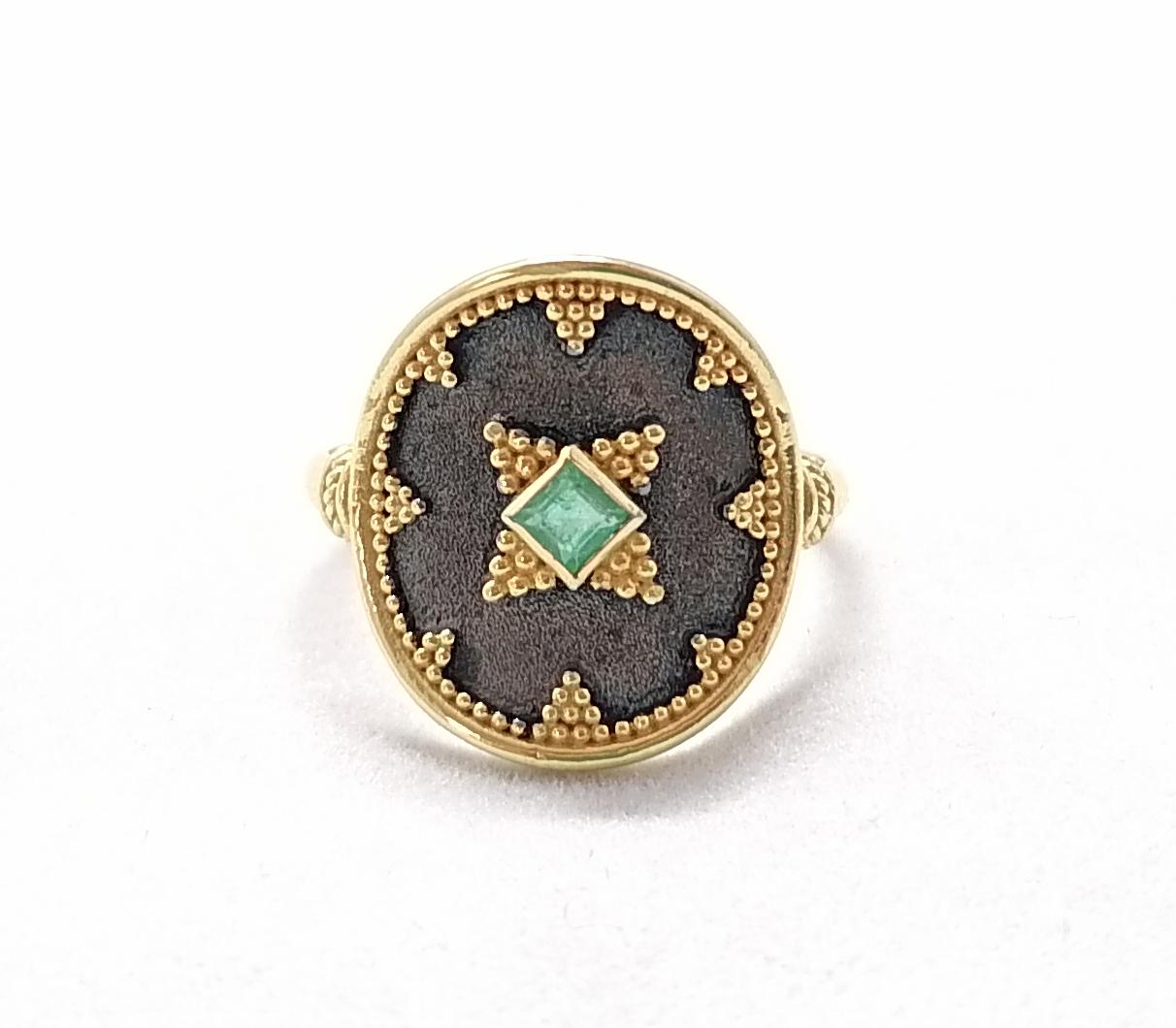 Cette superbe bague bicolore du designer S.Georgios est fabriquée à la main en or jaune 18 carats massif et est décorée au microscope d'un travail de granulation de style byzantin. Cette magnifique bague présente au centre une élégante émeraude