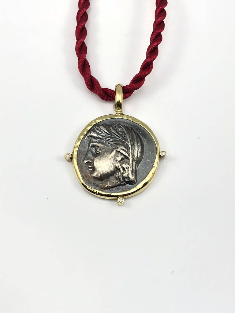 This S.Georgios designer 18 Karat Yellow Gold handmade Coin Pendant Necklace of Dimitra featuring 6 Brilliant cut Diamonds (3 on the front side and 3 on the backside) with a total weight of 0.06 Carat and a replica of an Ancient Greek Coin of