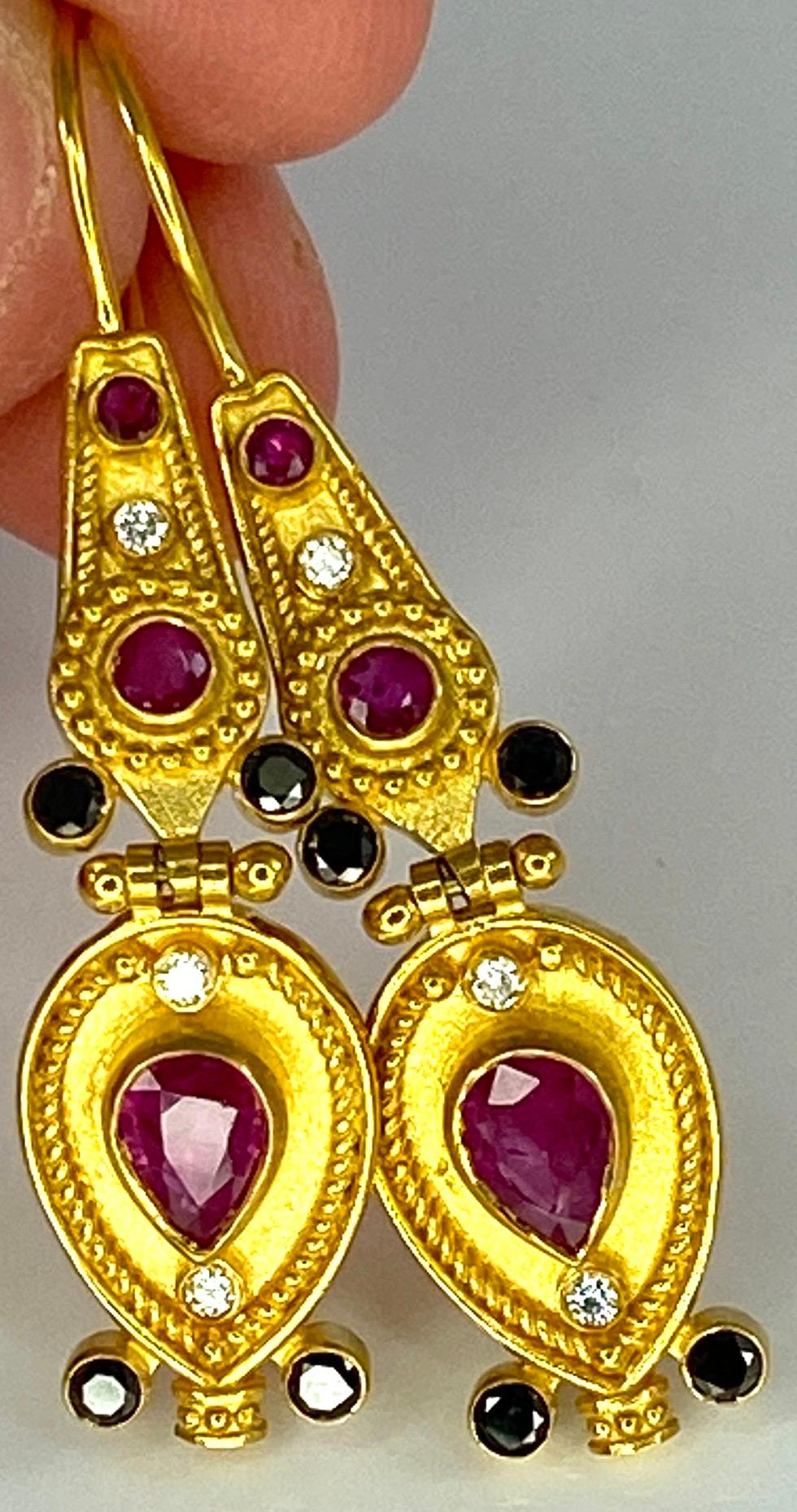 Die Ohrringe aus 18 Karat Gelbgold im byzantinischen Stil von S.Georgios werden in mikroskopischer Granulationsarbeit von Hand gefertigt und mit einem einzigartigen Samtuntergrund versehen. 
Das wunderschöne Paar besteht aus 2 natürlichen Rubinen im