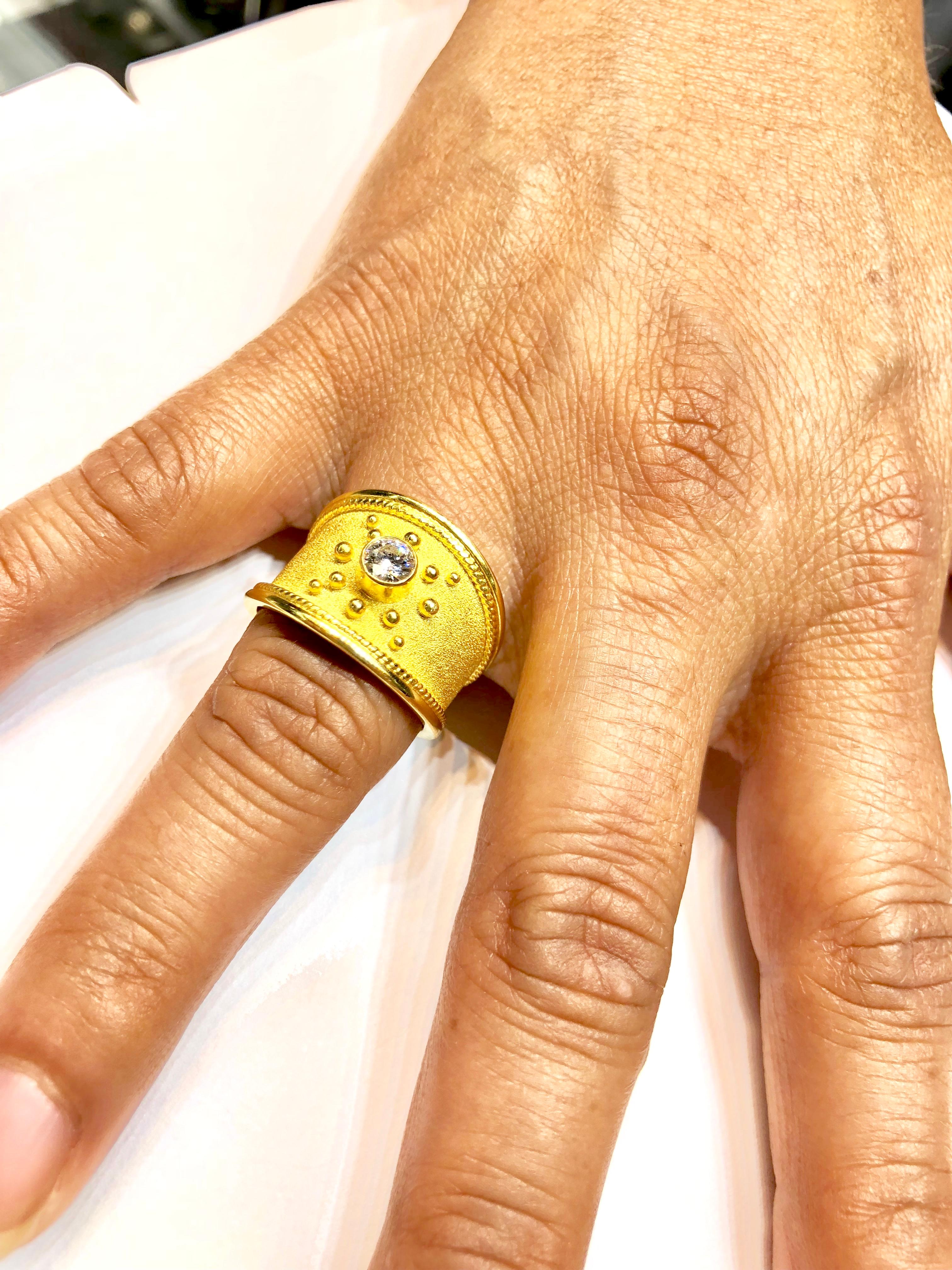 Bague en or jaune 18 carats du designer S.Georgios, décorée à la main avec un savoir-faire byzantin. La bague est ornée d'un travail de granulation sur tout le pourtour et d'un fond de velours unique. Elle comporte un diamant taille brillant d'un