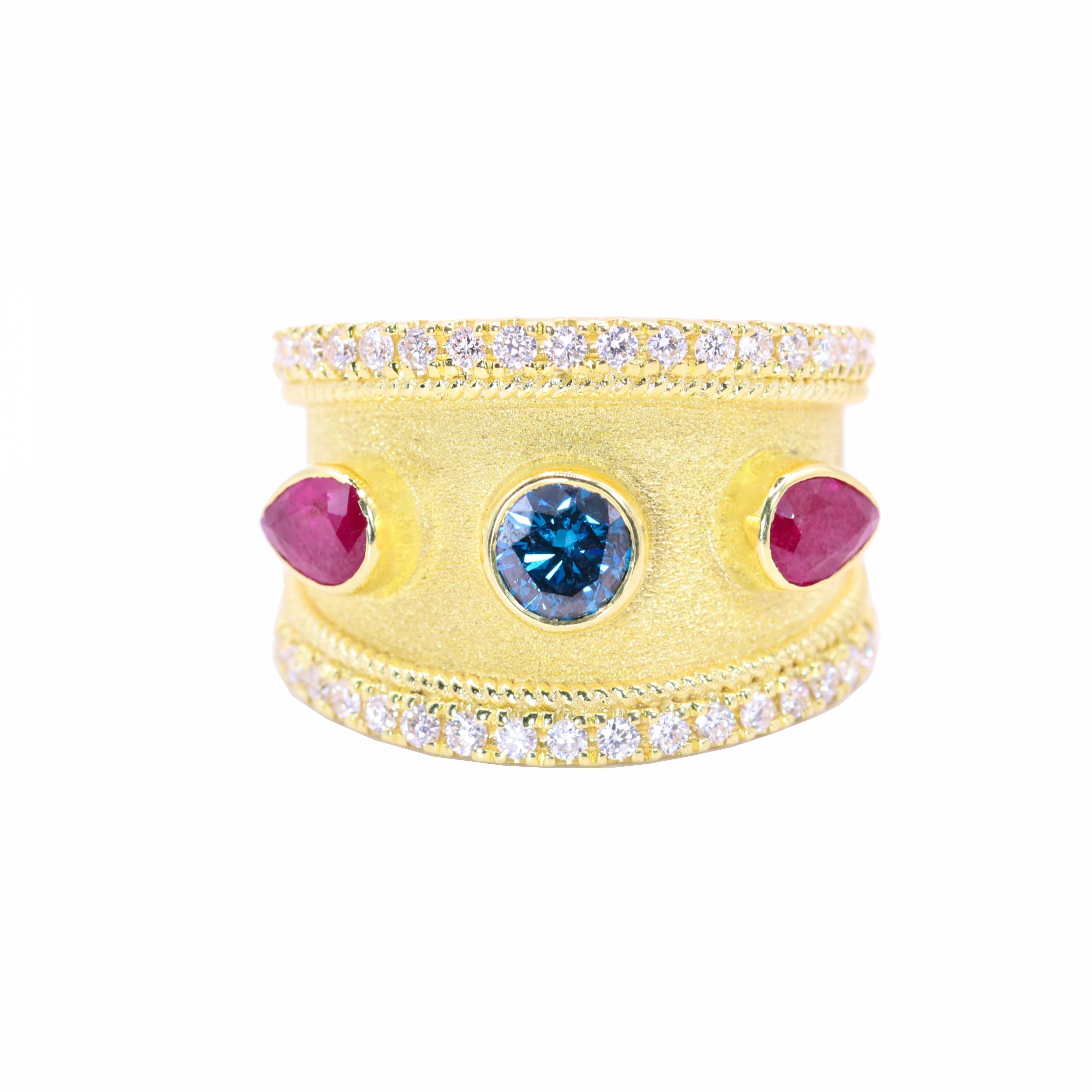 El diseñador S.Georgios presenta un elegante anillo de Oro Amarillo de 18 Kilates con un impresionante Diamante Azul talla brillante de 0,58 acompañado en las dos caras por dos Rubíes talla Pera con un peso total de 0,98 Quilates. Este anillo tiene