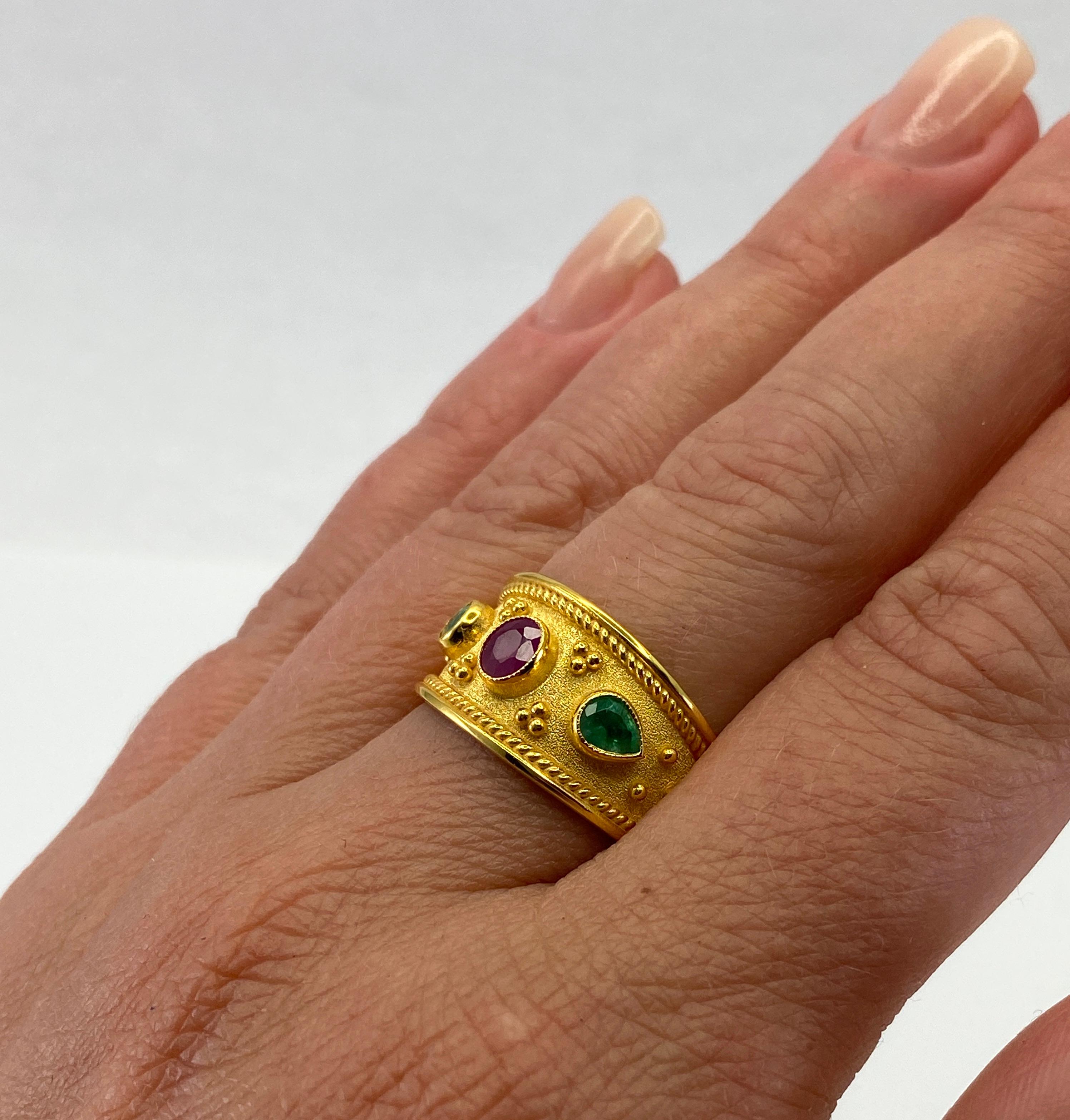 Presenting S.Georgios designer 18 Karat Solid Yellow Gold Ring all handmade in Byzantine Style workmanship with a unique velvet background and granulation. This ring features 0.56 Carat oval cut Ruby in the center and 2 pear shape Emeralds total