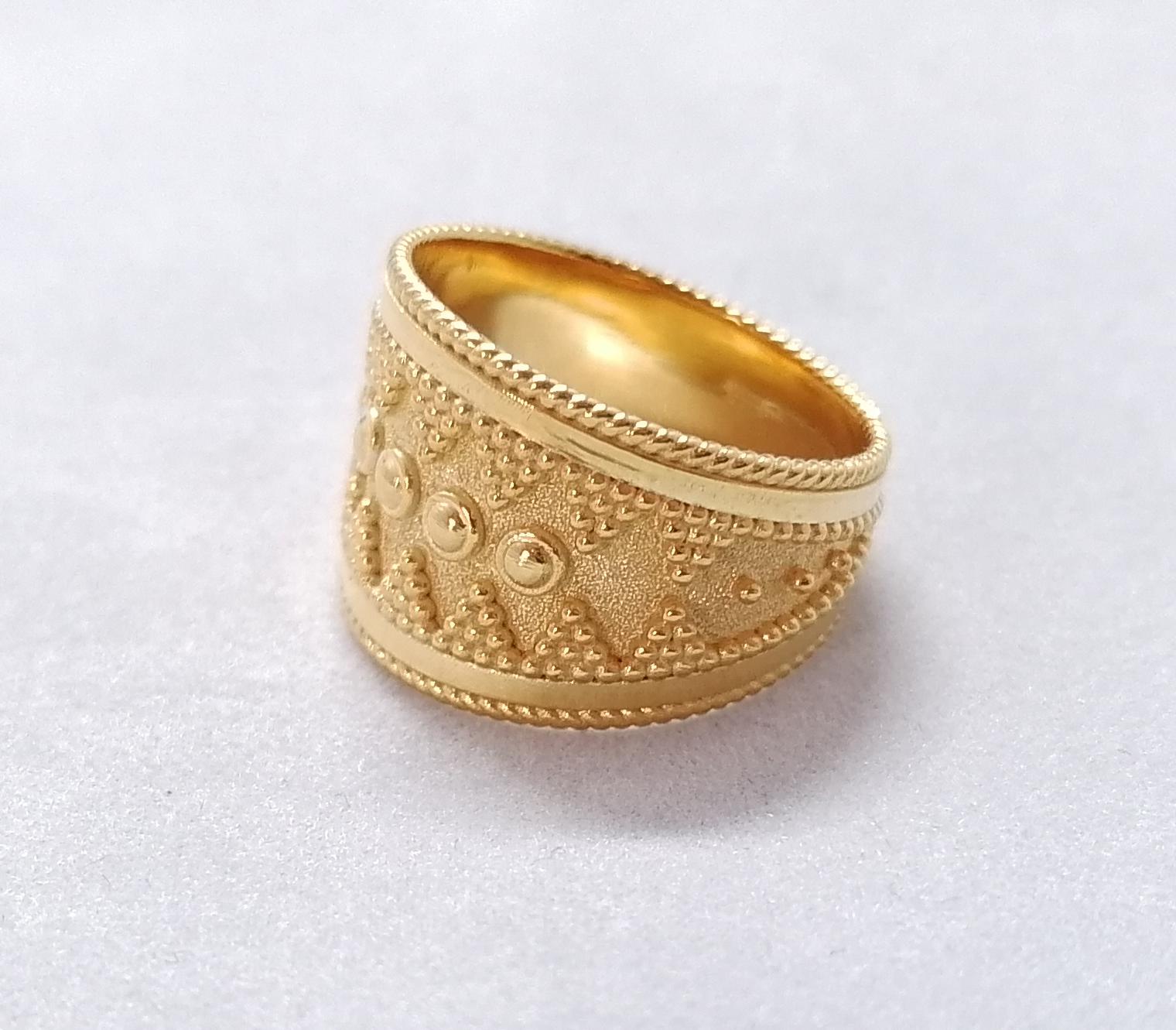 This S.Georgios designer wide band ring is made from solid 18 Karat Yellow Gold and is microscopically decorated with handmade granulation work to create a stunning and elegant art piece. We have finished this beautiful band with a stunning unique