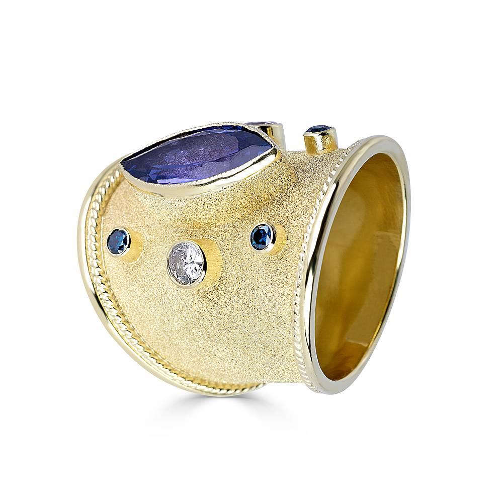 One of a kind S.Georgios design Hand Made 18 Karat Yellow Gold Ring decorated with Byzantine-style granulation and unique velvet look on the background. The ring features a 3.59 Carat Center Marquise Natural Tanzanite, two Brilliant Cut White