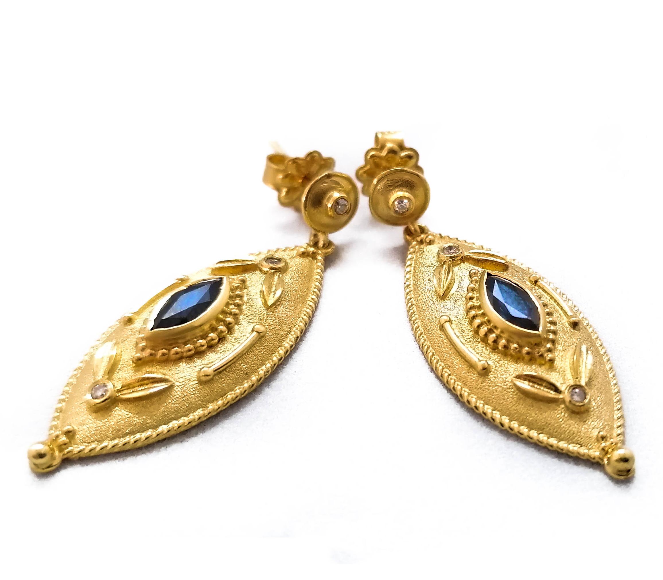 These S.Georgios designers Etruscan-style 18 Karat Yellow Gold earrings are hand made with granulation workmanship done microscopically and are finished with a unique velvet background. The gorgeous pair feature 2 marquise-cut natural Blue