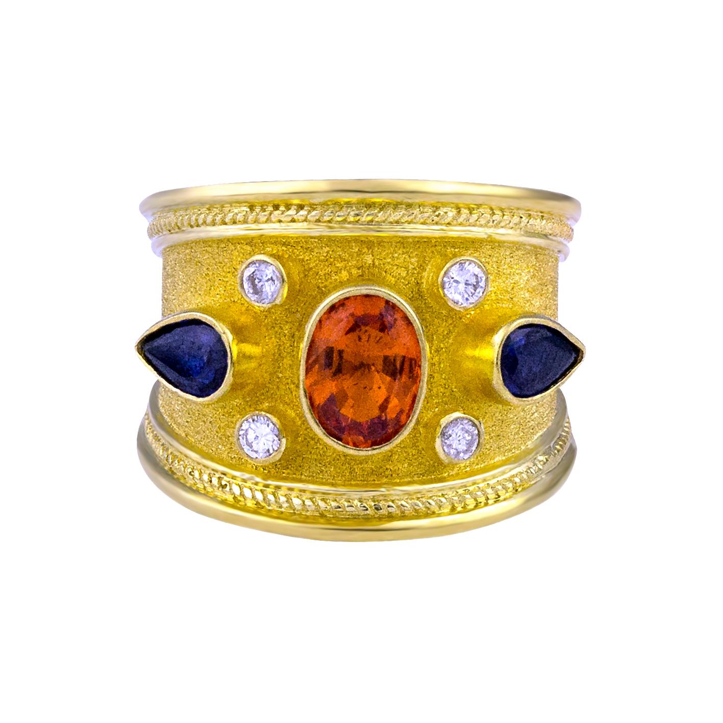 S.Georgios Hand Made 18 Karat Yellow Gold Ring decorated with Byzantine-style granulation and the unique velvet finish on the background. The stunning ring features 4 Diamonds total weight of 0.20 Carat and 3 Sapphires. In the center, we have an