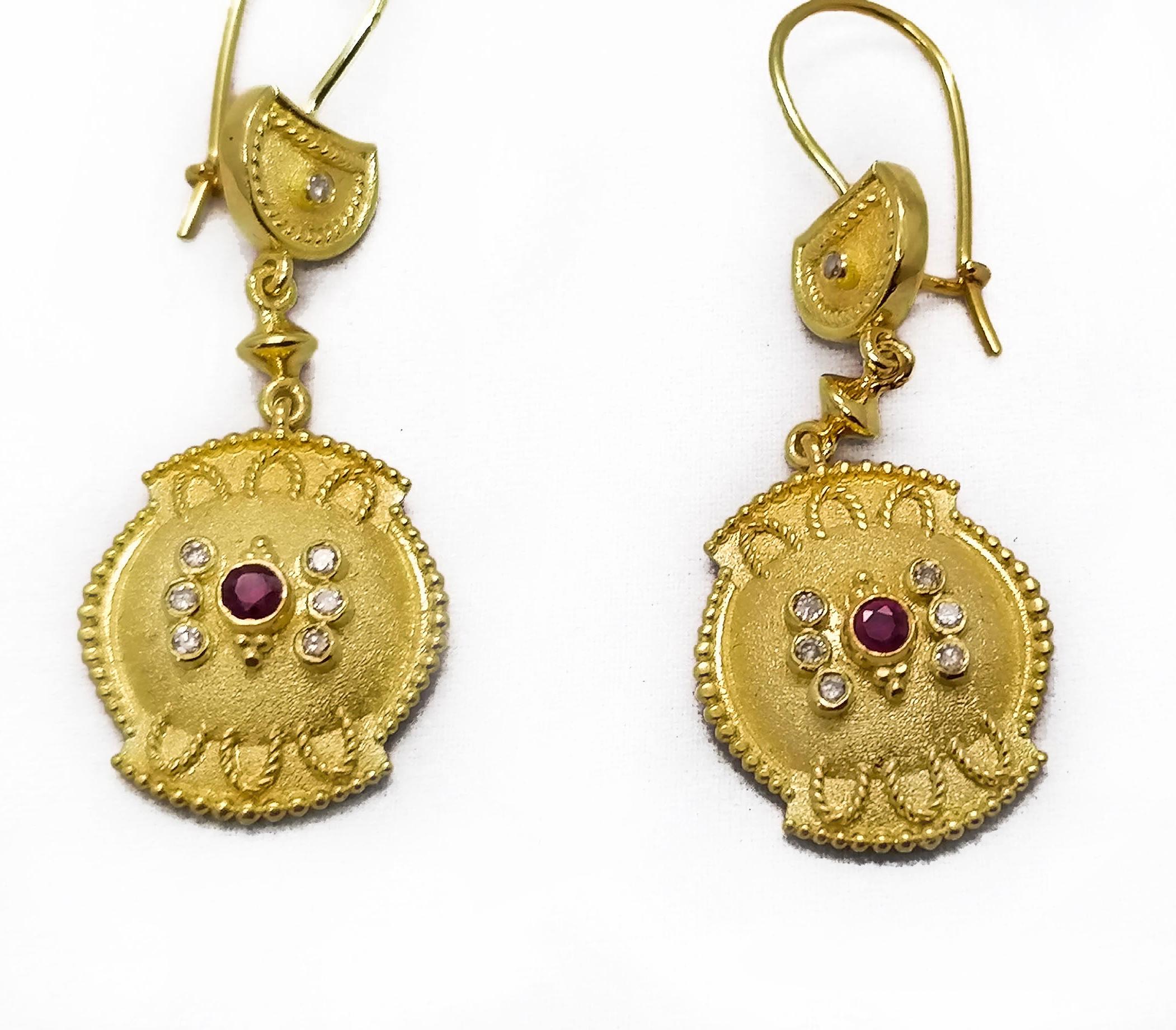 These S.Georgios designer earrings are hand made from 18 Karat Yellow Gold and decorated with Byzantine-era style granulation workmanship done all microscopically. This stunning pair of dangle earrings feature 2 brilliant-cut natural Rubies total