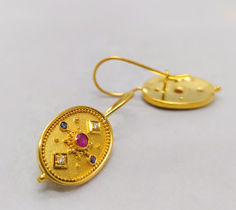 S.Georgios designer oval drop earrings are hand-made from 18 Karat Yellow Gold and decorated with Byzantine-era style granulation workmanship. These beautiful earrings feature 2 brilliant-cut Rubies with a total weight of 0.20 Carat surrounded by 4