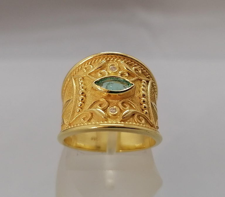 This S.Georgios designer Band Ring is 18 Karat Yellow Gold and all handmade with Byzantine bead granulation and a unique velvet background finished. This gorgeous band ring features a Marquise cut natural Emerald total weight of 0.29 Carat