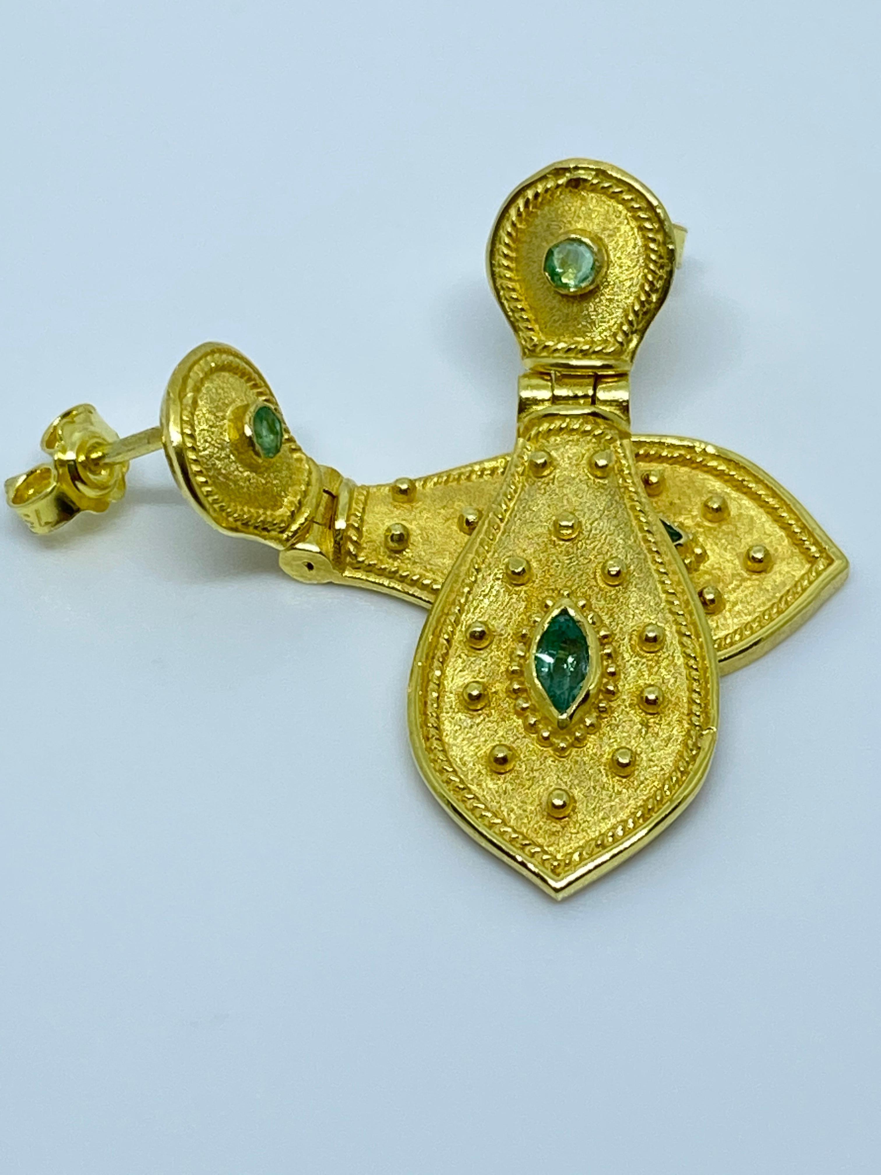Questi orecchini firmati S.Georgios sono realizzati a mano in oro giallo 18 carati e sono decorati con una lavorazione a granulazione in stile bizantino e presentano 4 smeraldi naturali per un peso totale di 0,67 carati. Questo splendido paio di