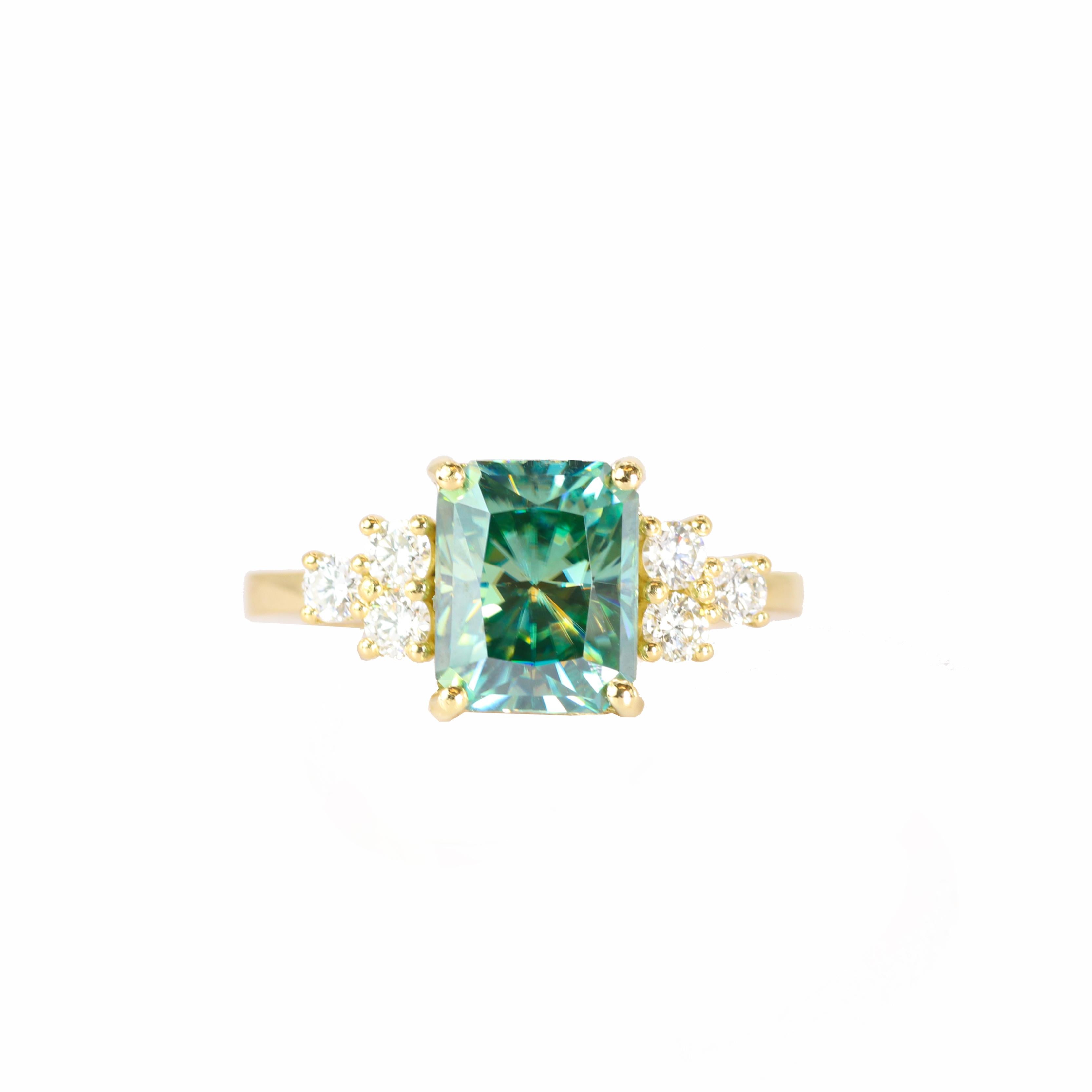 El diseñador S.Georgios presenta un exquisito Anillo de Oro Amarillo de 18 Kilates con una Moissanita talla esmeralda de 3,52 Quilates en su centro, enmarcada por seis brillantes Diamantes Blancos, con un peso total de 0,55 Quilates. La moissanita