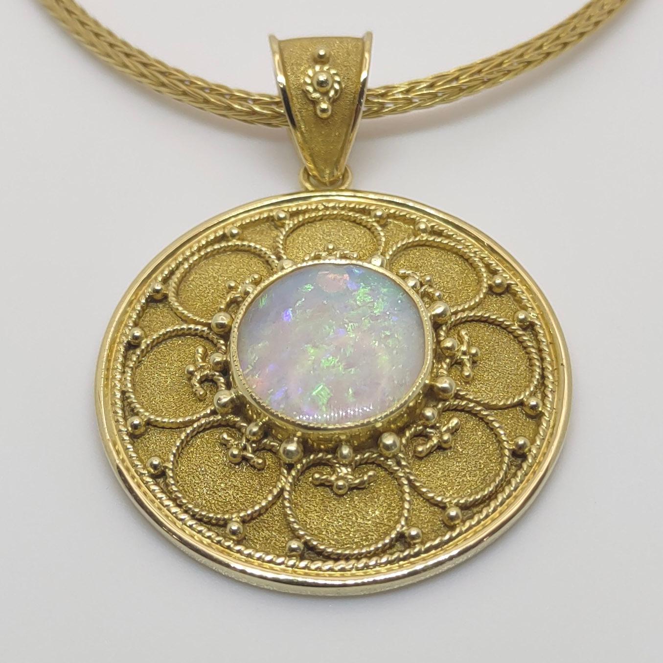 This S.Georgios designer pendant enhancer is handmade in 18 Karat yellow gold. It is microscopically decorated with granulation work beads and wires and has a gorgeous unique velvet background. This unique gorgeous round pendant enhancer features an
