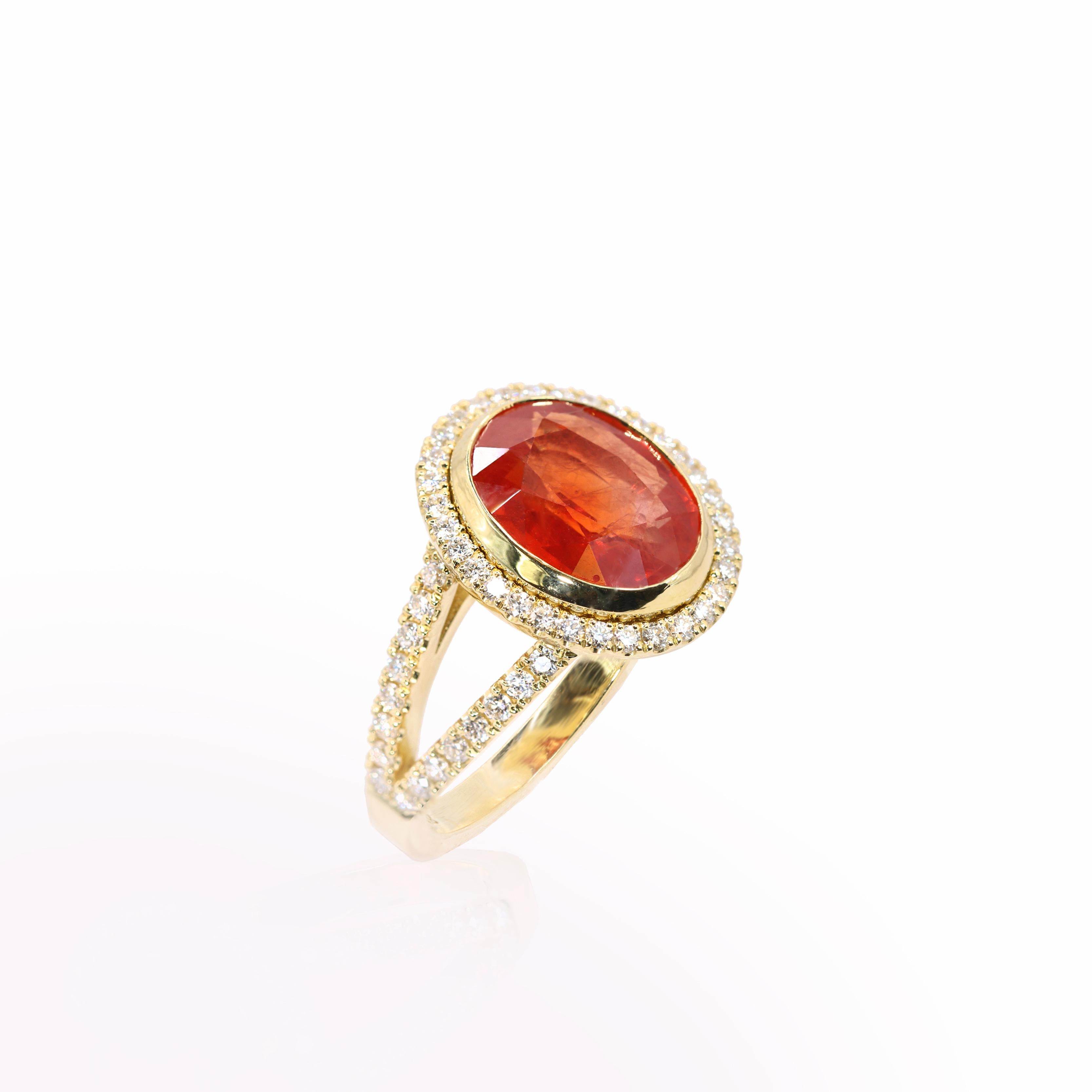 S.Georgios designer presents an exquisite 18K Yellow Gold Ring featuring an oval-cut 4,92 Carats Orange Sapphire at its center. This vibrant gemstone is elegantly surrounded by brilliant cut diamonds, total weight of 0.70 carats.  Handmade in