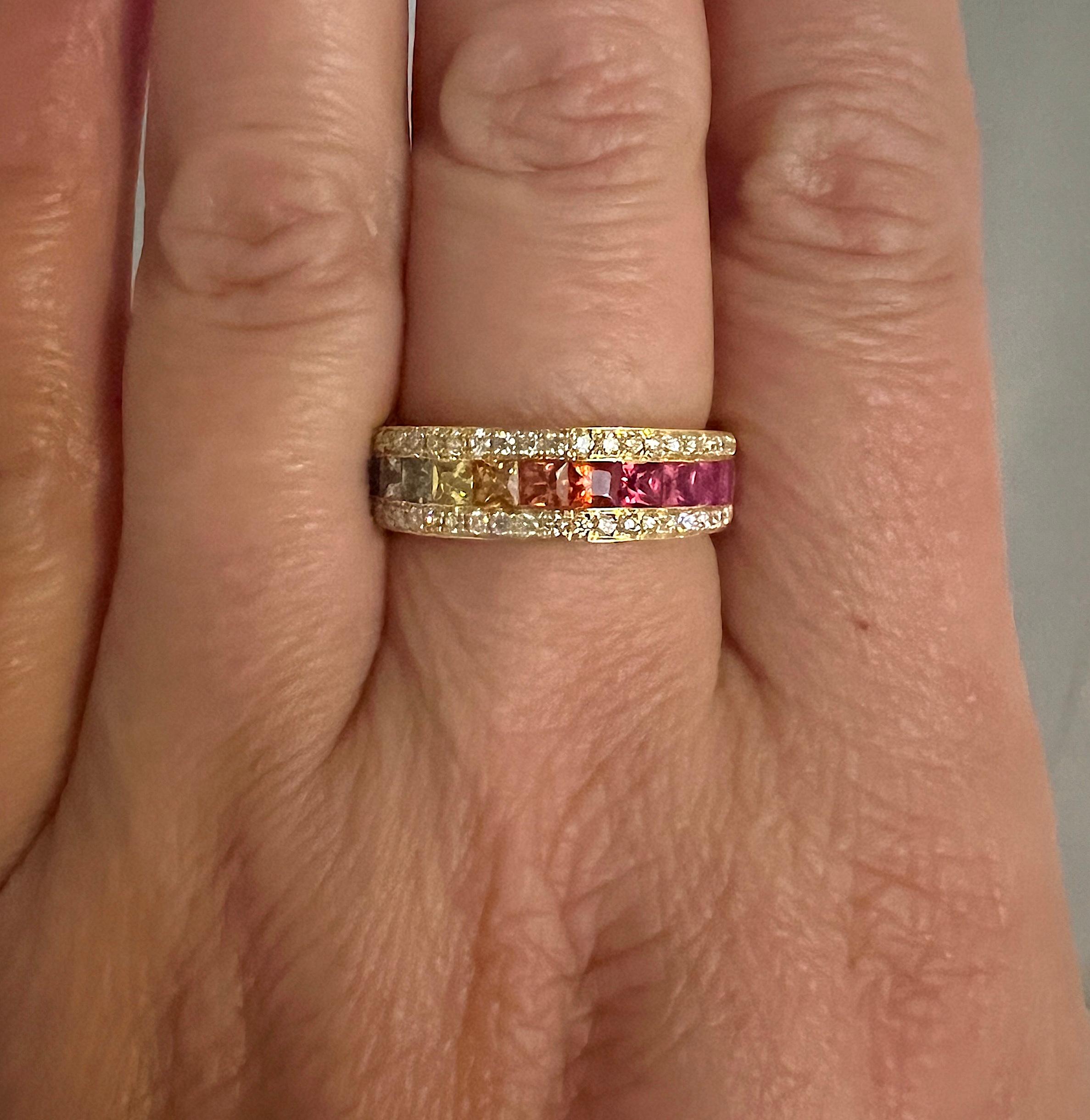 S. Georgios designer offers 18 Karat Yellow Gold Band Ring featuring 1.7 Carats of princess cut Multicolor Sapphires set in an invisible setting creating a beautiful rainbow. On the edges of a channel setting are two lines of White Diamonds with a