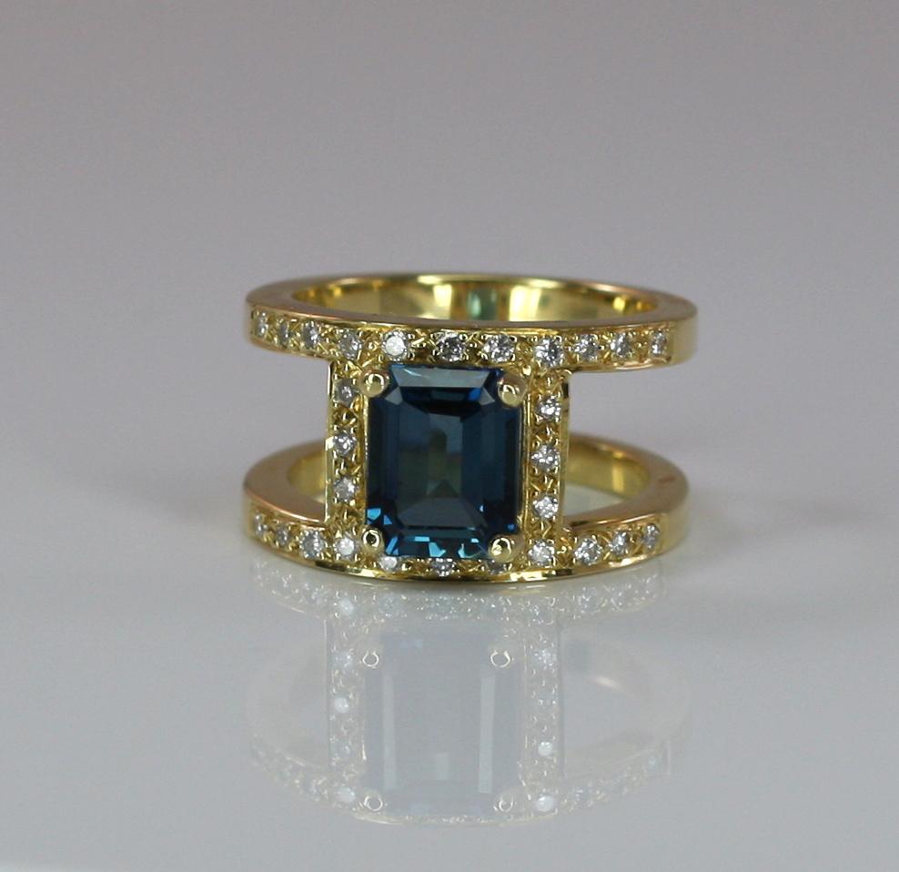 S.Georgios designer 18 Karat Solid Yellow Gold Wide Ring is all handmade in our workshop in Greece. This gorgeous band ring features an emerald-cut London Blue Topaz total weight of 2.93 Carat and 0.30 Carat brilliant cut White Diamonds.
The