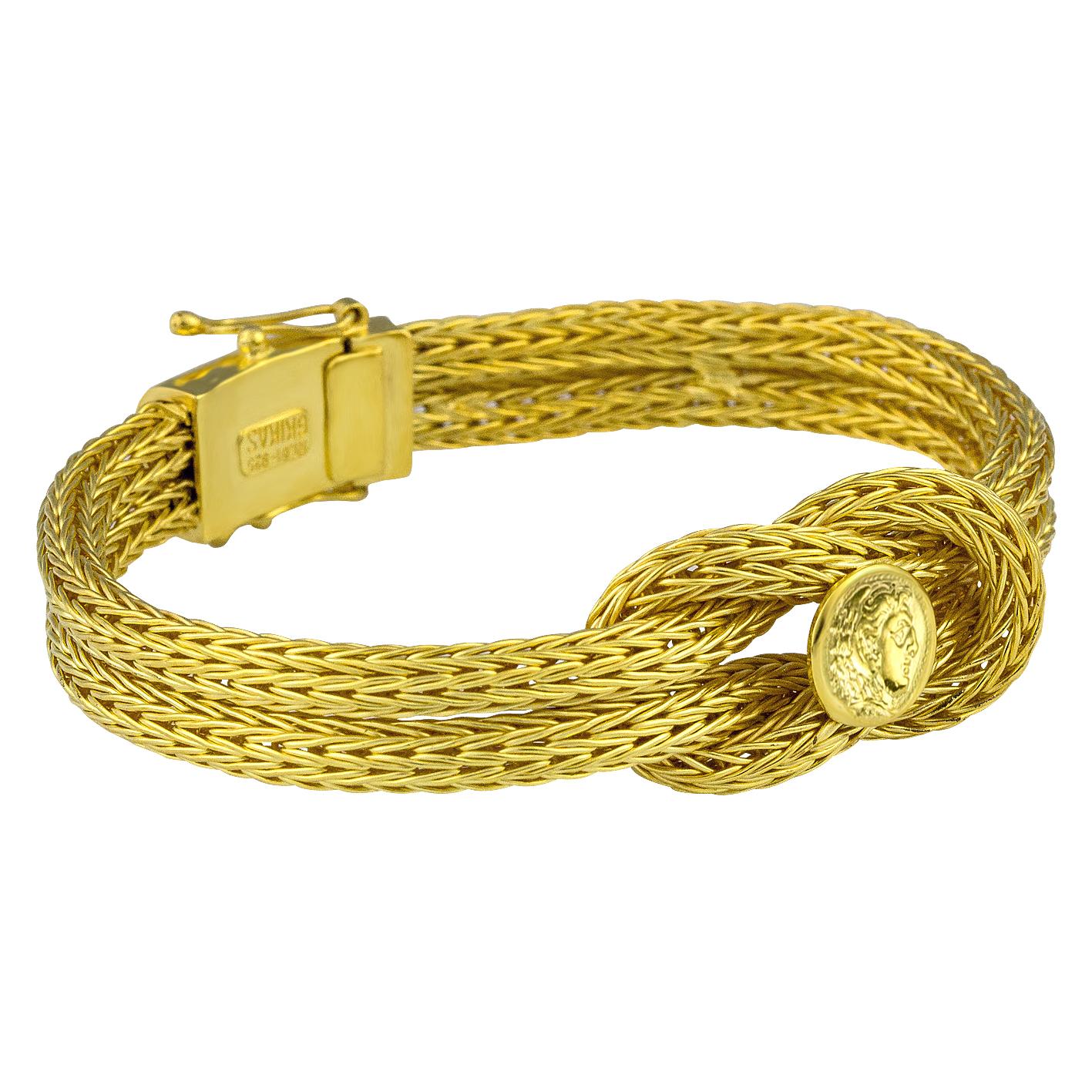 Bracelet de créateur S.Georgios tricoté à la main dans notre atelier en Grèce à partir de fils d'or jaune 18 carats, tous fabriqués sur mesure. Ce bracelet souple est orné du nœud d'Hercule, symbole de force, de guérison et de protection, et d'une