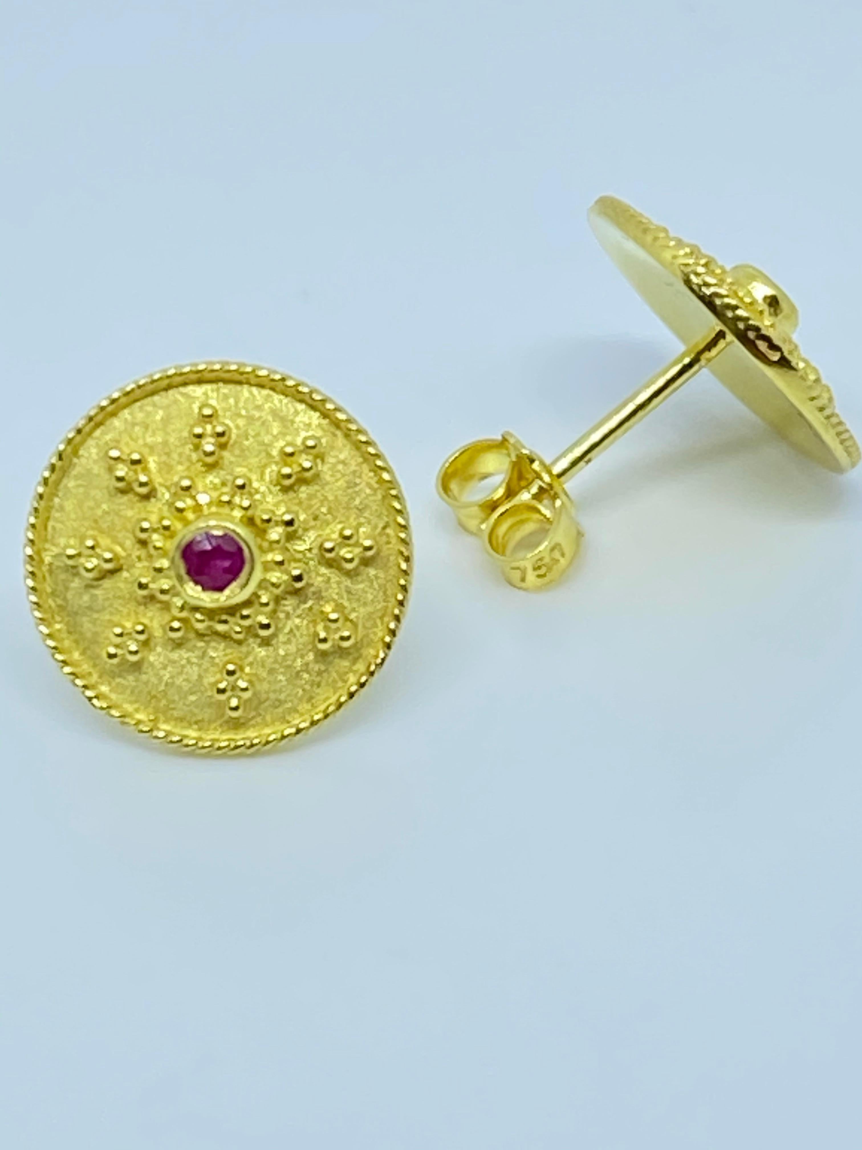 These S.Georgios designer earrings are hand made from 18 Karat Yellow Gold and decorated with Byzantine-era style bead granulation workmanship. These beautiful stud earrings feature 2 Brilliant cut Rubies total weight of 0.05 Carat and are finished