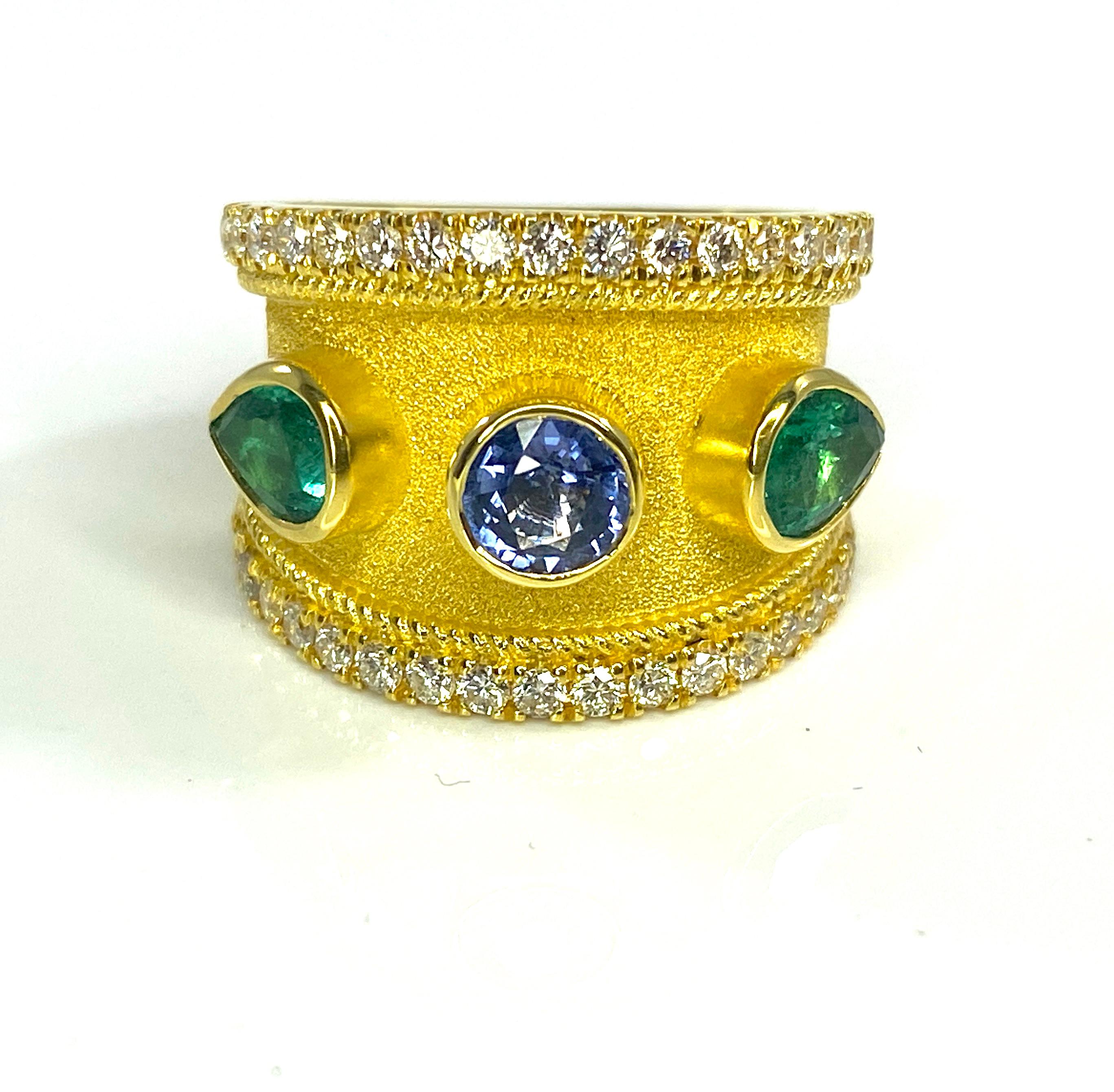 This is a stunning S.Georgios designer Ring in 18 Karat Yellow Gold all decorated with a Byzantine velvet background. The center of this gorgeous ring features 0.64 Carat Brilliant cut Blue Sapphire and 2 pear shape Emeralds on the side in total