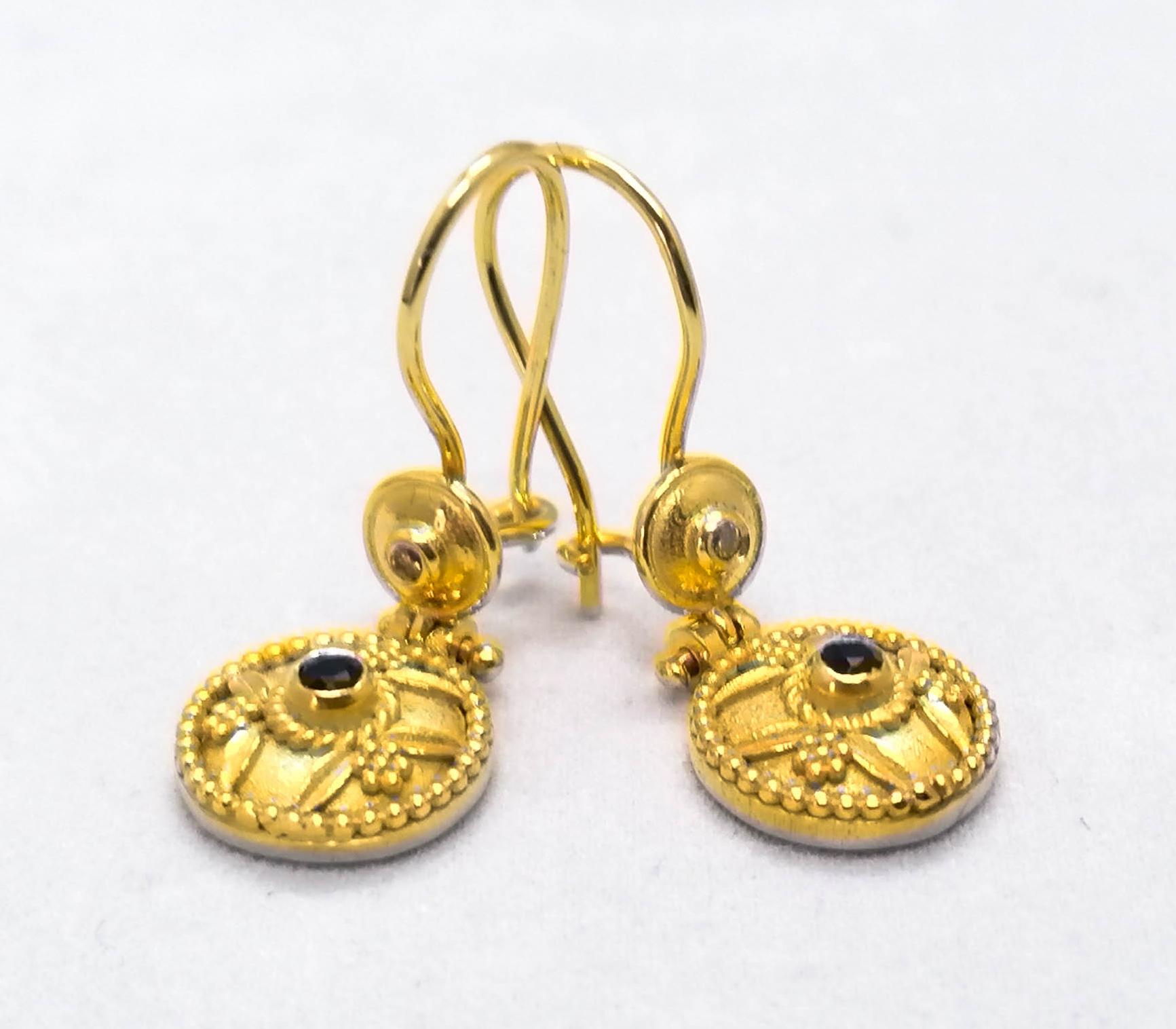 These S.Georgios 18 Karat Yellow Gold designer earrings are decorated with hand made Byzantine-era style bead granulation workmanship, and finished with a unique velvet background. These beautiful earrings feature 2 brilliant-cut natural Blue