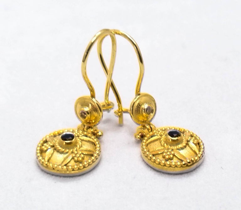These S.Georgios 18 Karat Yellow Gold designer earrings are decorated with hand made Byzantine-era style bead granulation workmanship, and finished with a unique velvet background. These beautiful earrings feature 2 brilliant-cut natural Blue