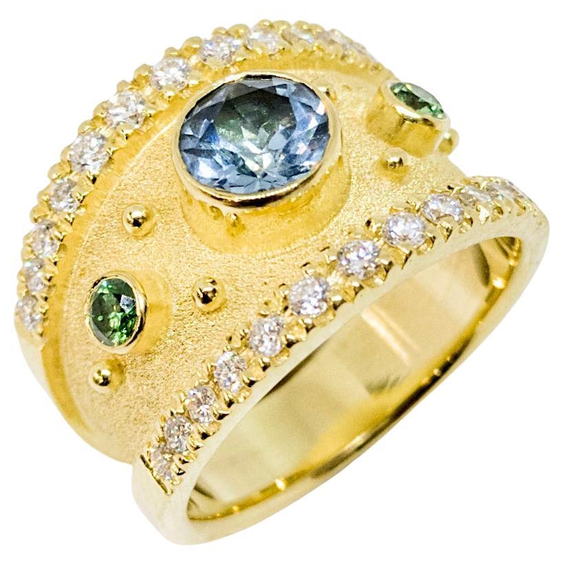 This is a stunning S.Georgios designer Solitaire Ring in Yellow Gold 18 Karat all decorated with a Byzantine velvet background and granulation details. The center of the ring features a beautiful 0.98 Carat Brilliant cut Blue Topaz accompanied by 2