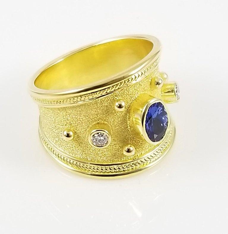 This S.Georgios designer 18 Karat solid Yellow Gold Band Ring is all handmade and has microscopic Byzantine granulation workmanship and a unique velvet background. The gorgeous ring features a center Oval cut Tanzanite total weight of 0,90 Carats