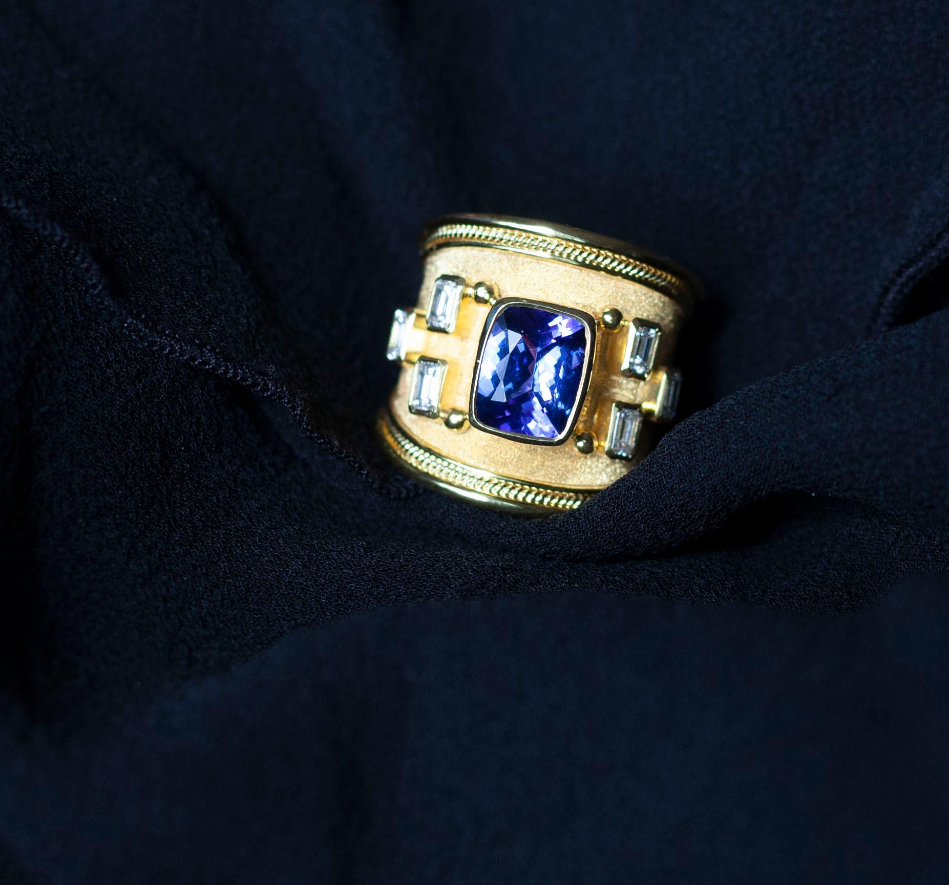 S.Georgios designer 18 Karat Yellow Gold Band Ring is all handmade with a Byzantine Granulation Workmanship and a unique velvet background. This gorgeous band features in the center a Cushion Cut Natural Tanzanite total weight of 3,48 Carats and 6